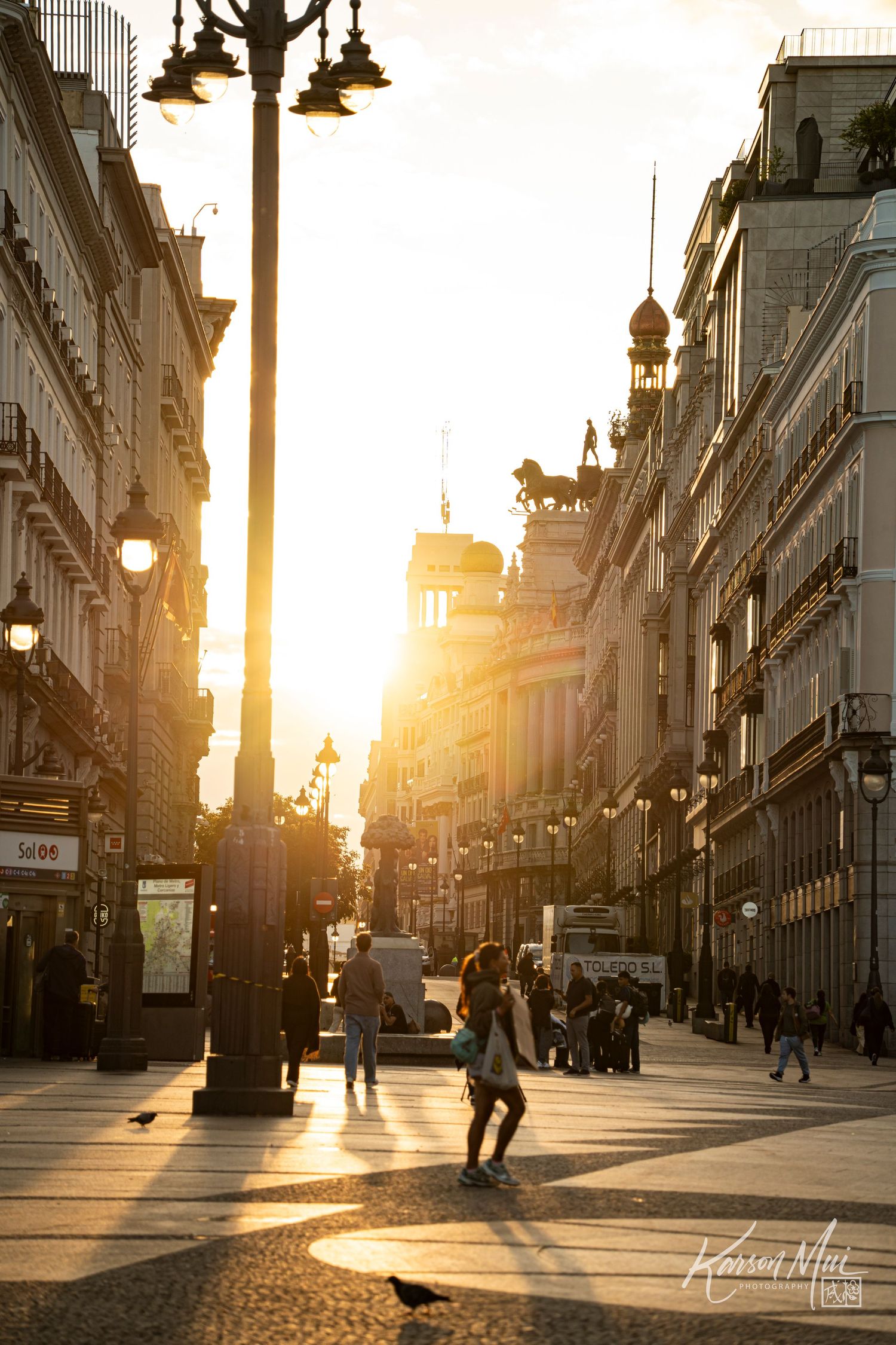 Golden sunset illuminates a bustling pedestrian street in Madrid, Spain.