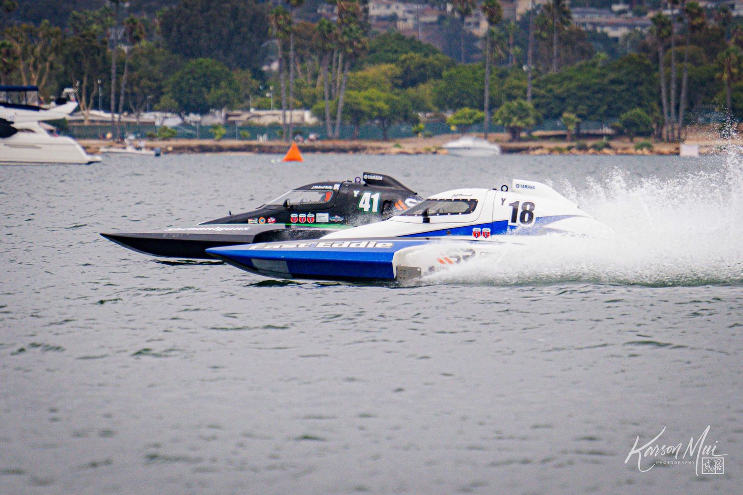Blue and white powerboats numbered 16 and 41 race side by side across open water in a competition.