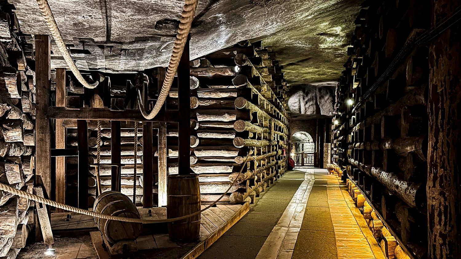 Underground salt mine tunnel with wooden support beams and rope lighting in Wieliczka, Poland.