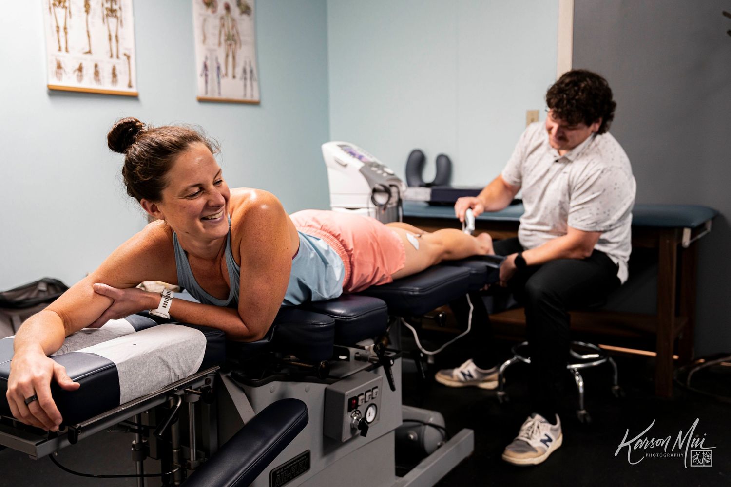 Woman smiling during chiropractic adjustment treatment on massage table in medical office.