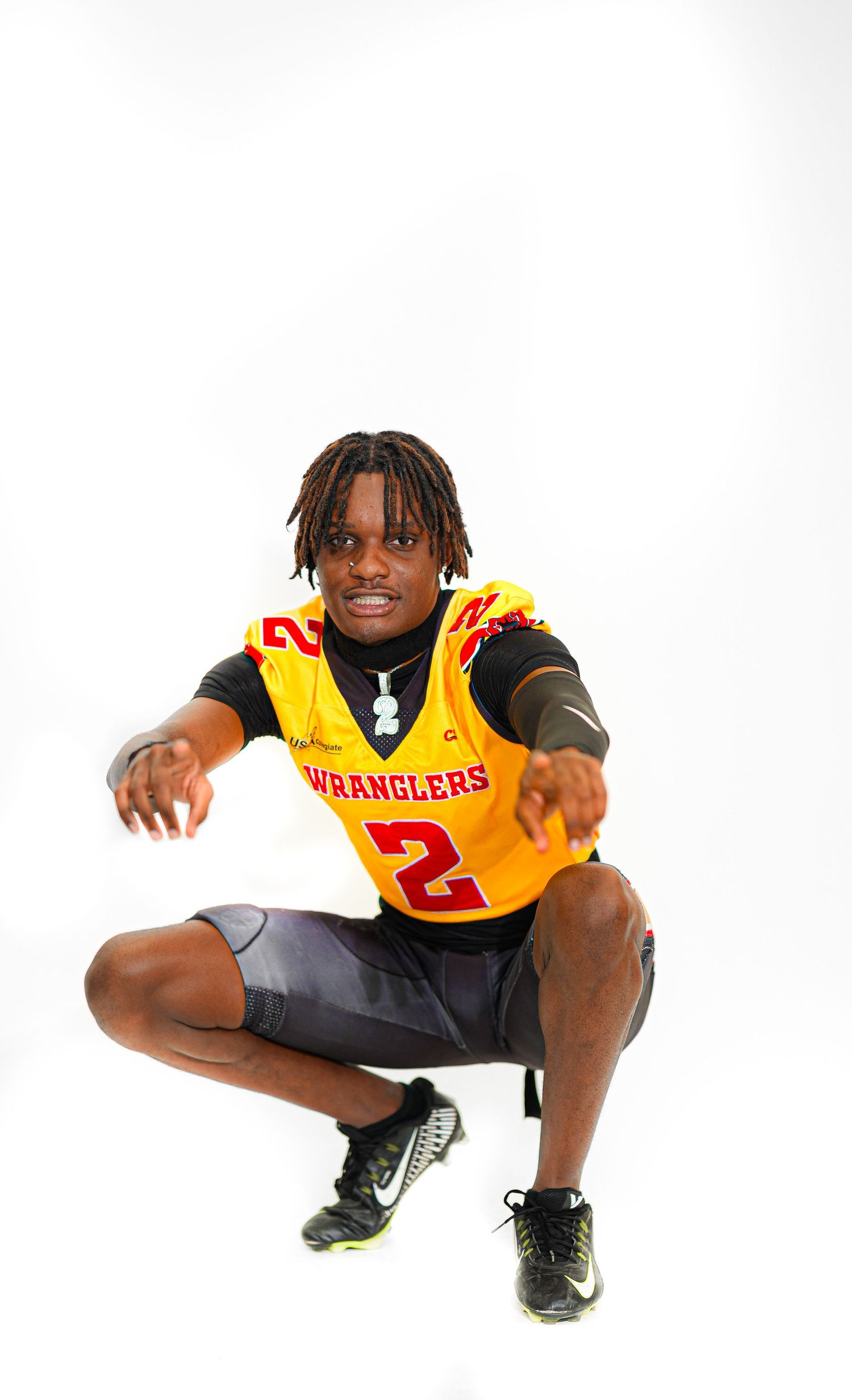 Football player wearing yellow Wranglers #2 jersey crouching in dynamic pose against white background.