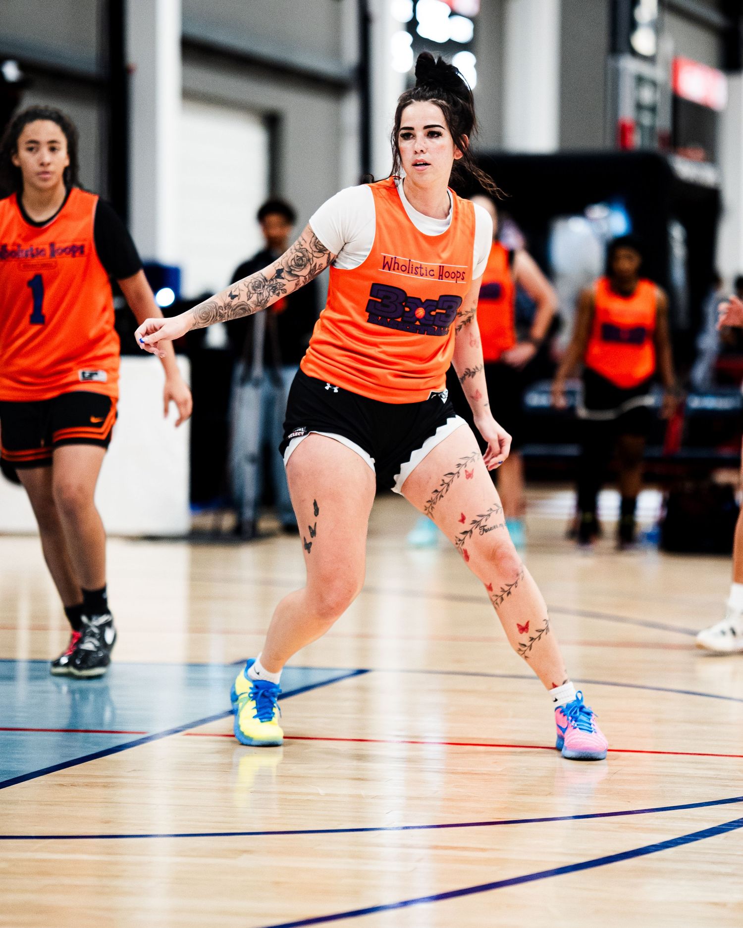 Female basketball player in orange jersey dribbling on indoor court during competitive game.