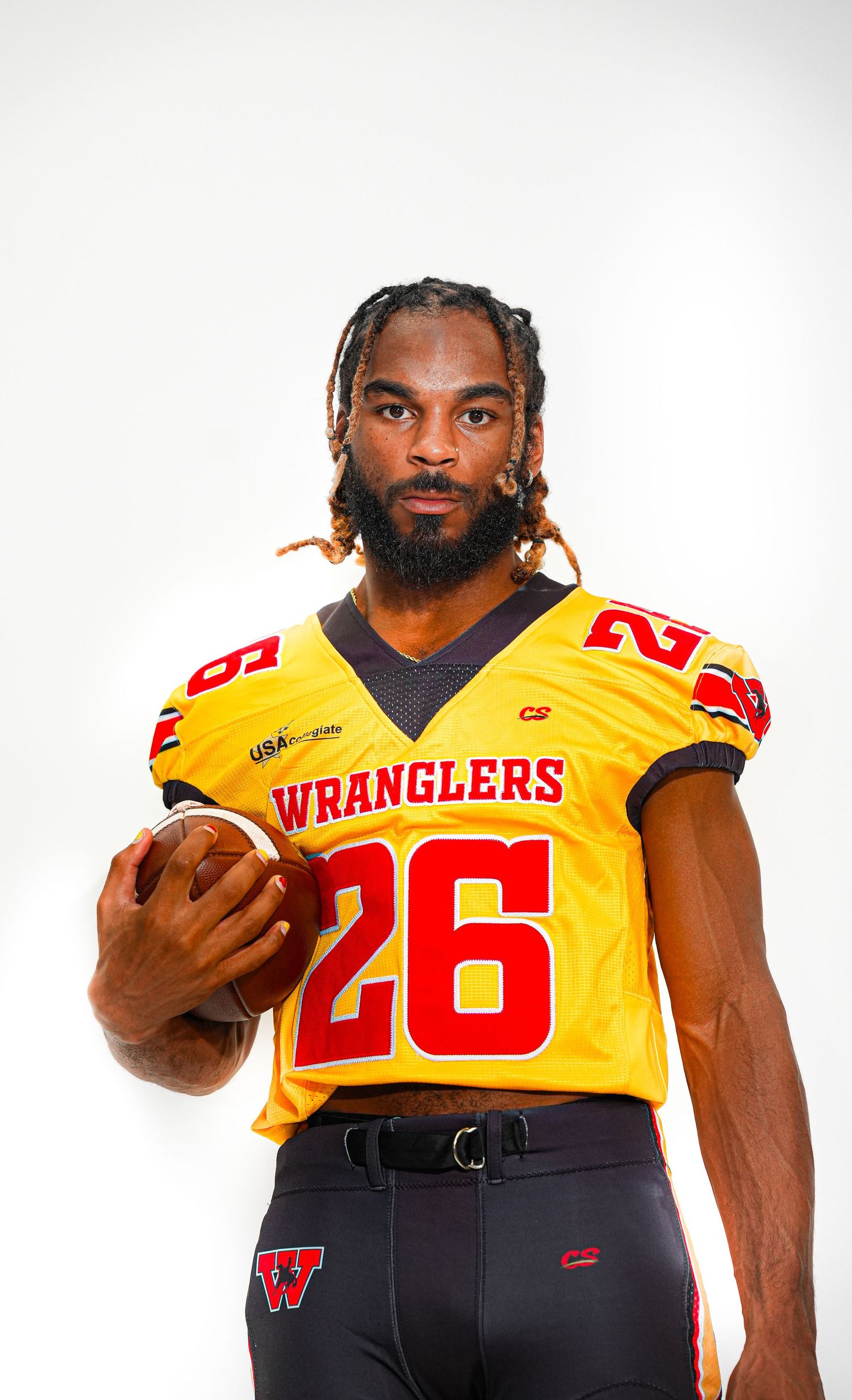 Wranglers football player #26 in gold jersey holding a football during a professional team photo shoot.