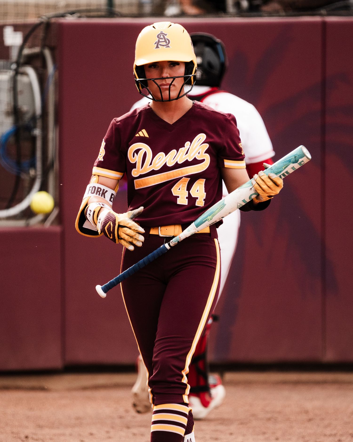 ASU softball player number 44 in maroon uniform walks with a bat during a Big 12 college softball game.