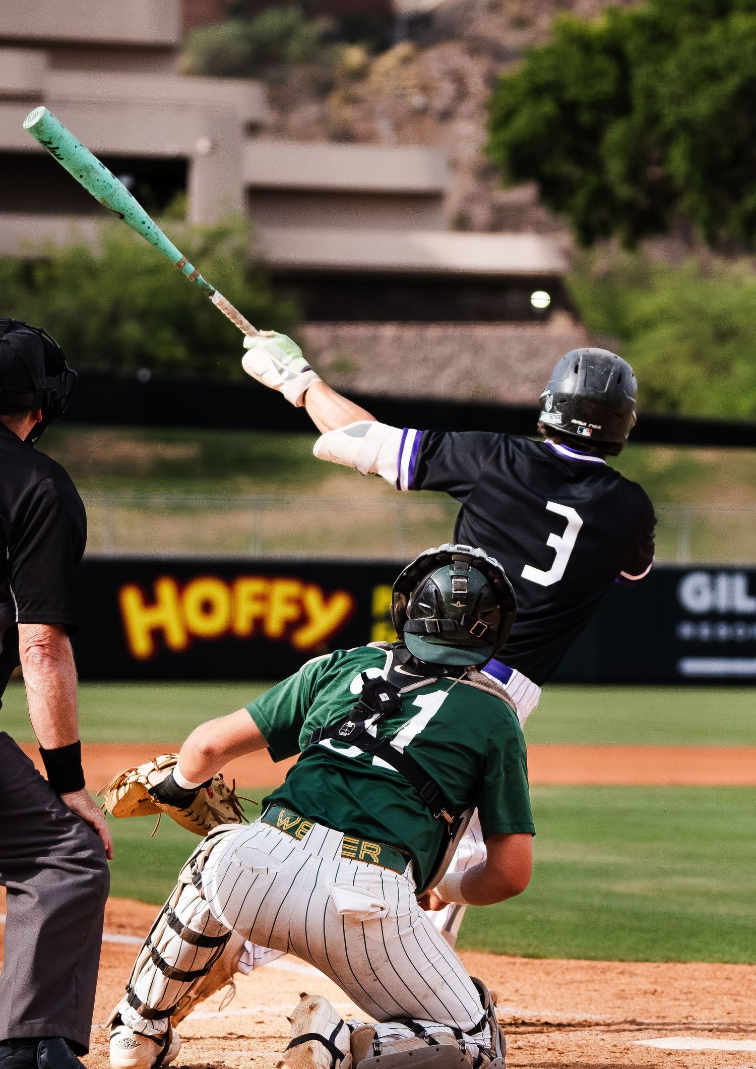 Baseball batter number 3 swings with a green bat as catcher number 21 crouches behind home plate.