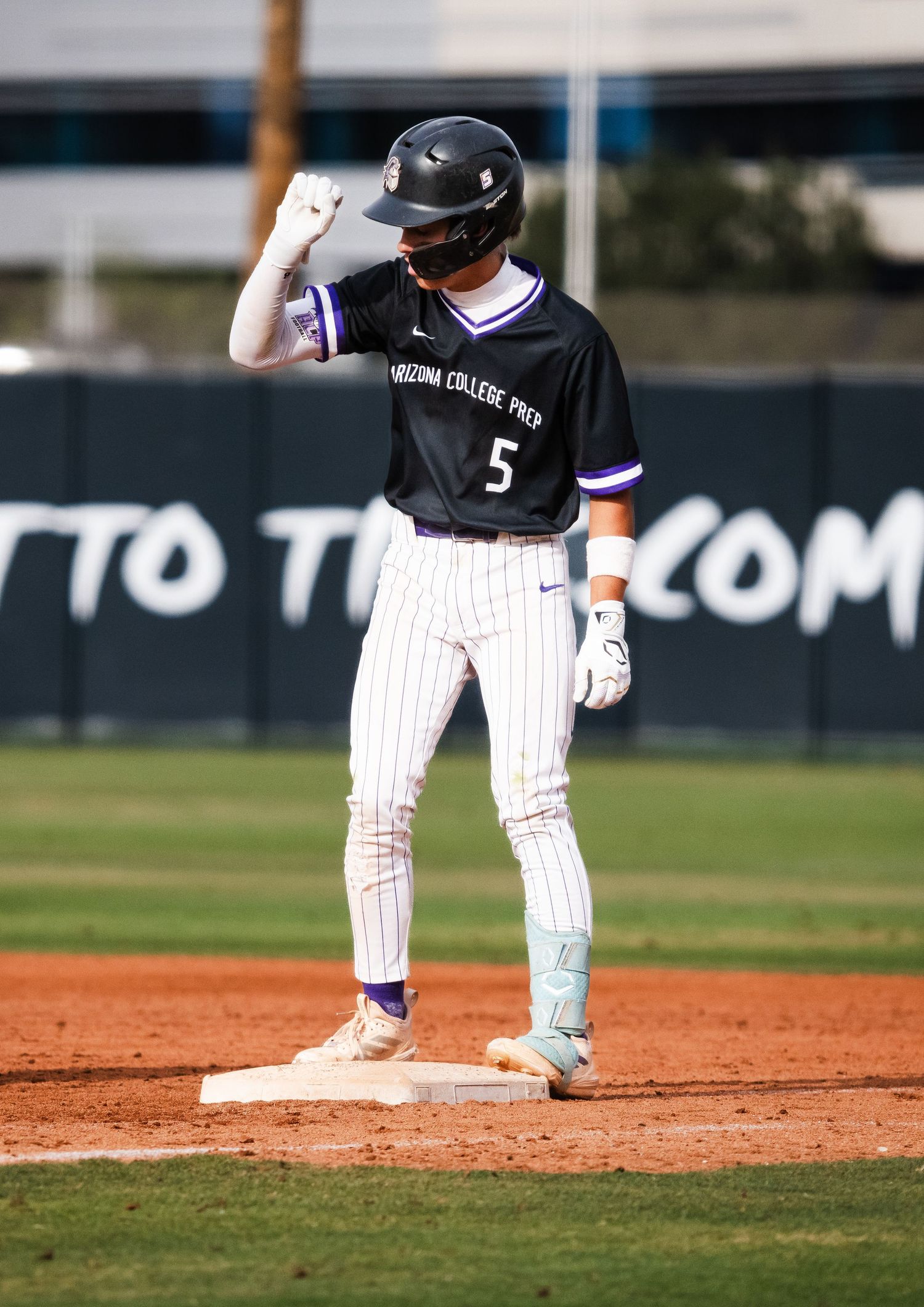 Baseball player #5 in Arizona College Prep uniform celebrates at second base during a sunny game.