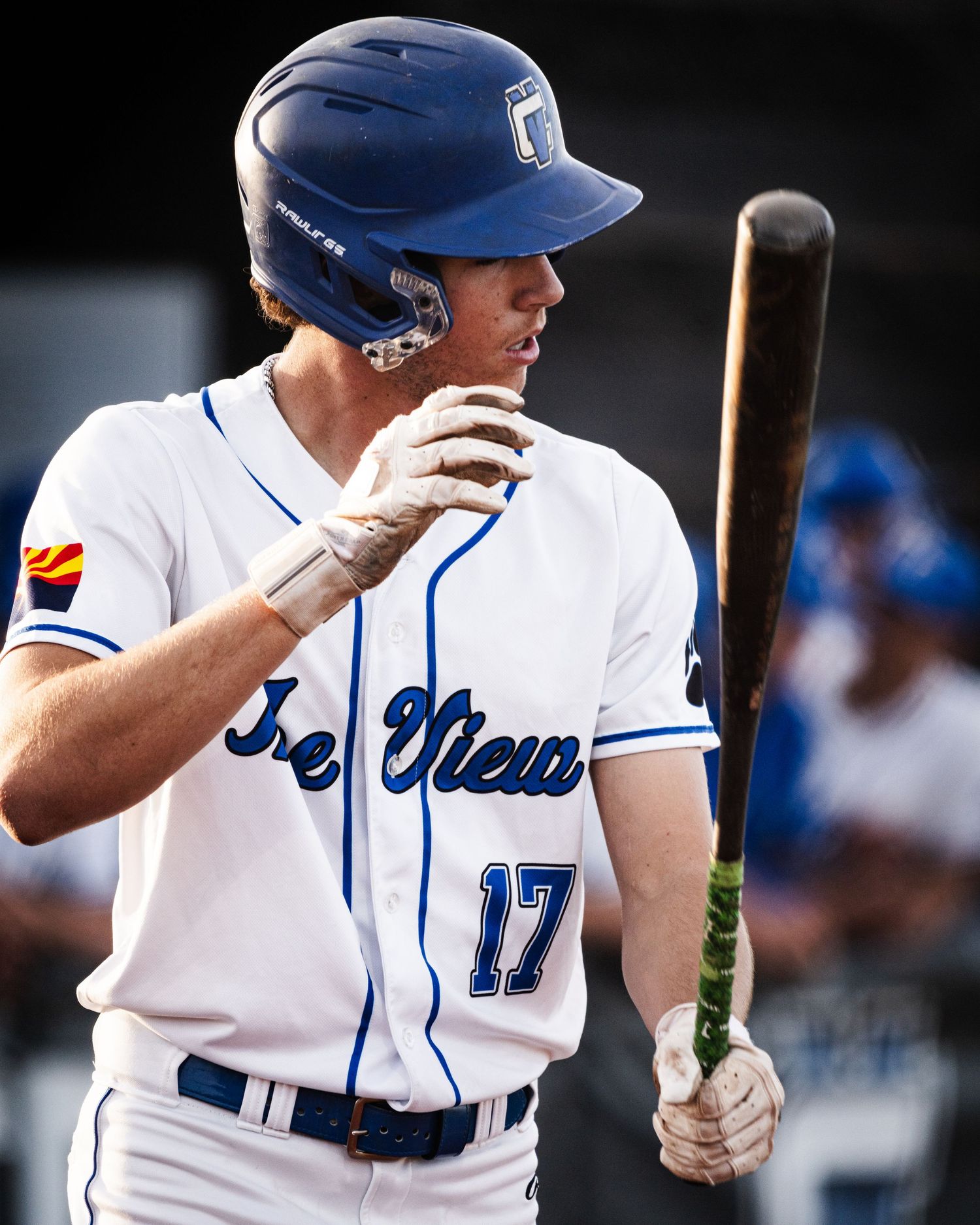 Baseball player wearing number 17 jersey and blue helmet holds bat during game.