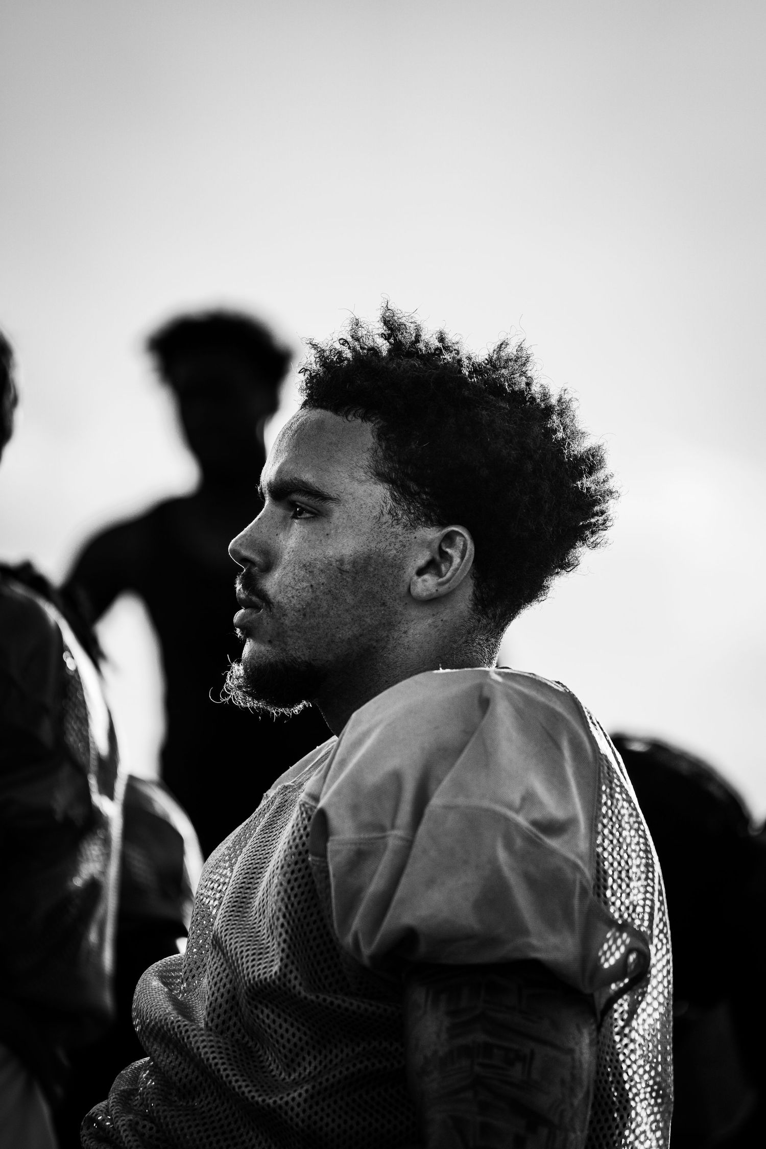 Black and white portrait of a young football player in jersey looking sideways during practice.