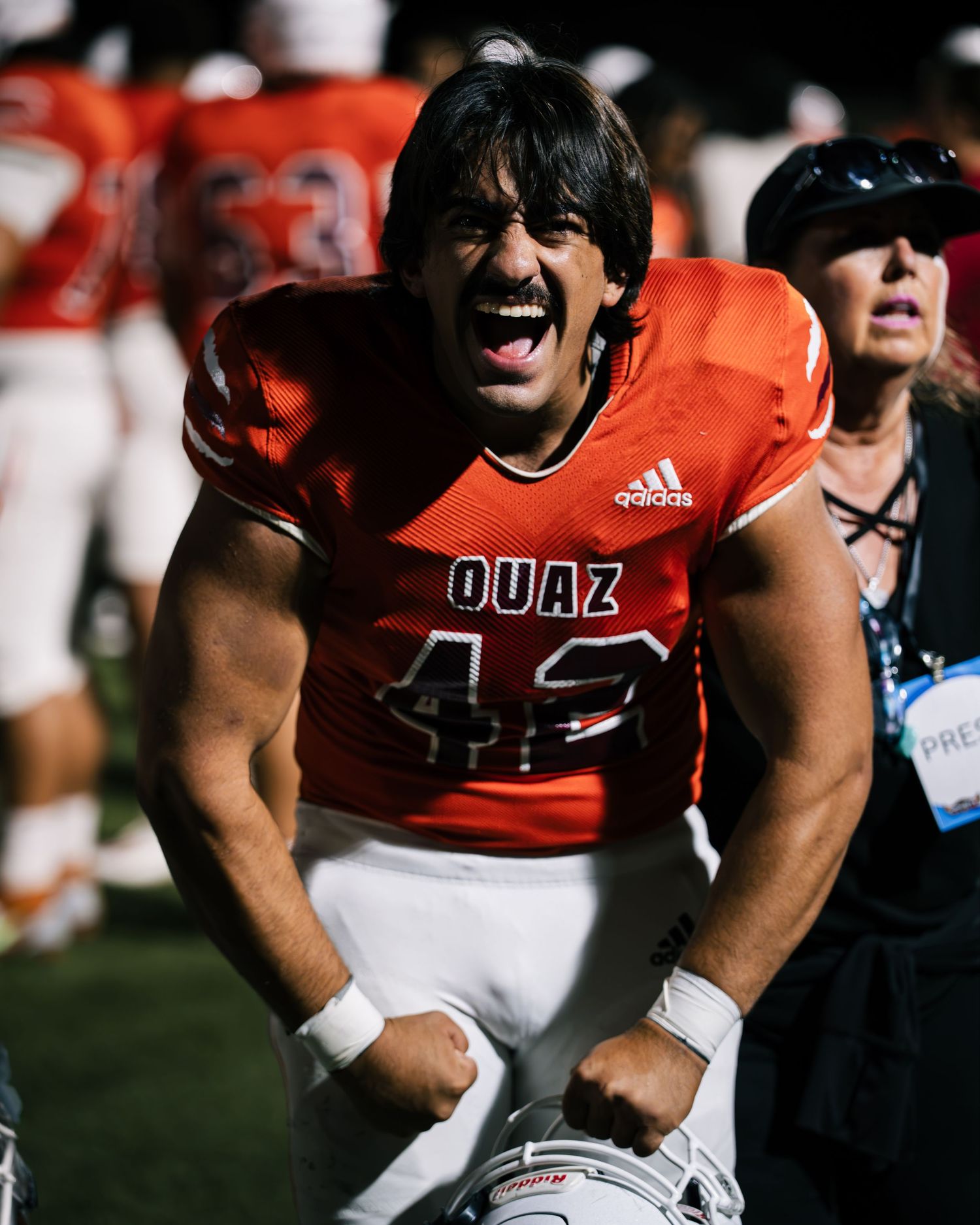 Football player in orange OUAZ jersey number 42 celebrates victory on the sideline during a game.