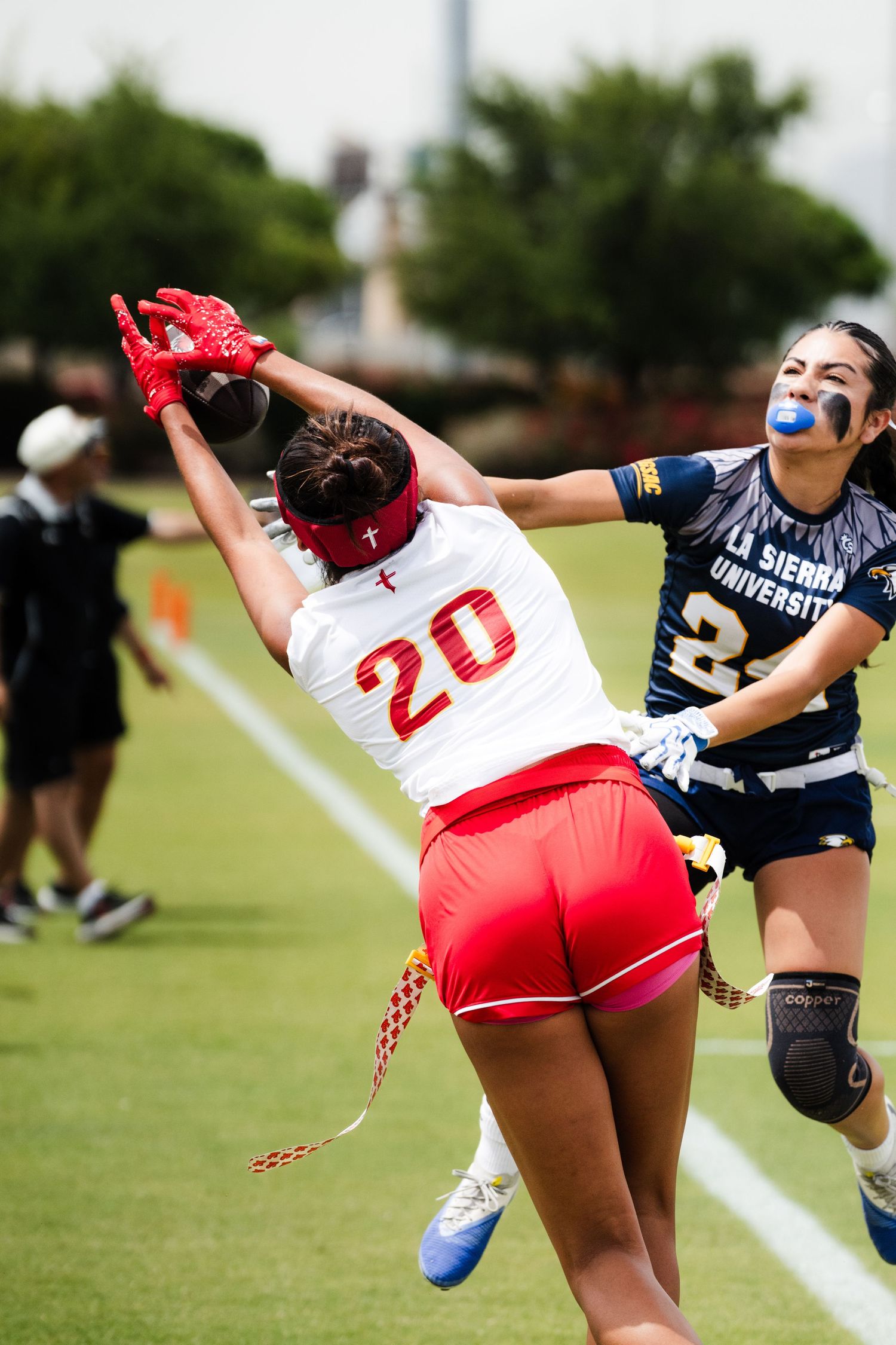 Two female flag football players compete for the ball during a game between Firestorm and Sierra University.