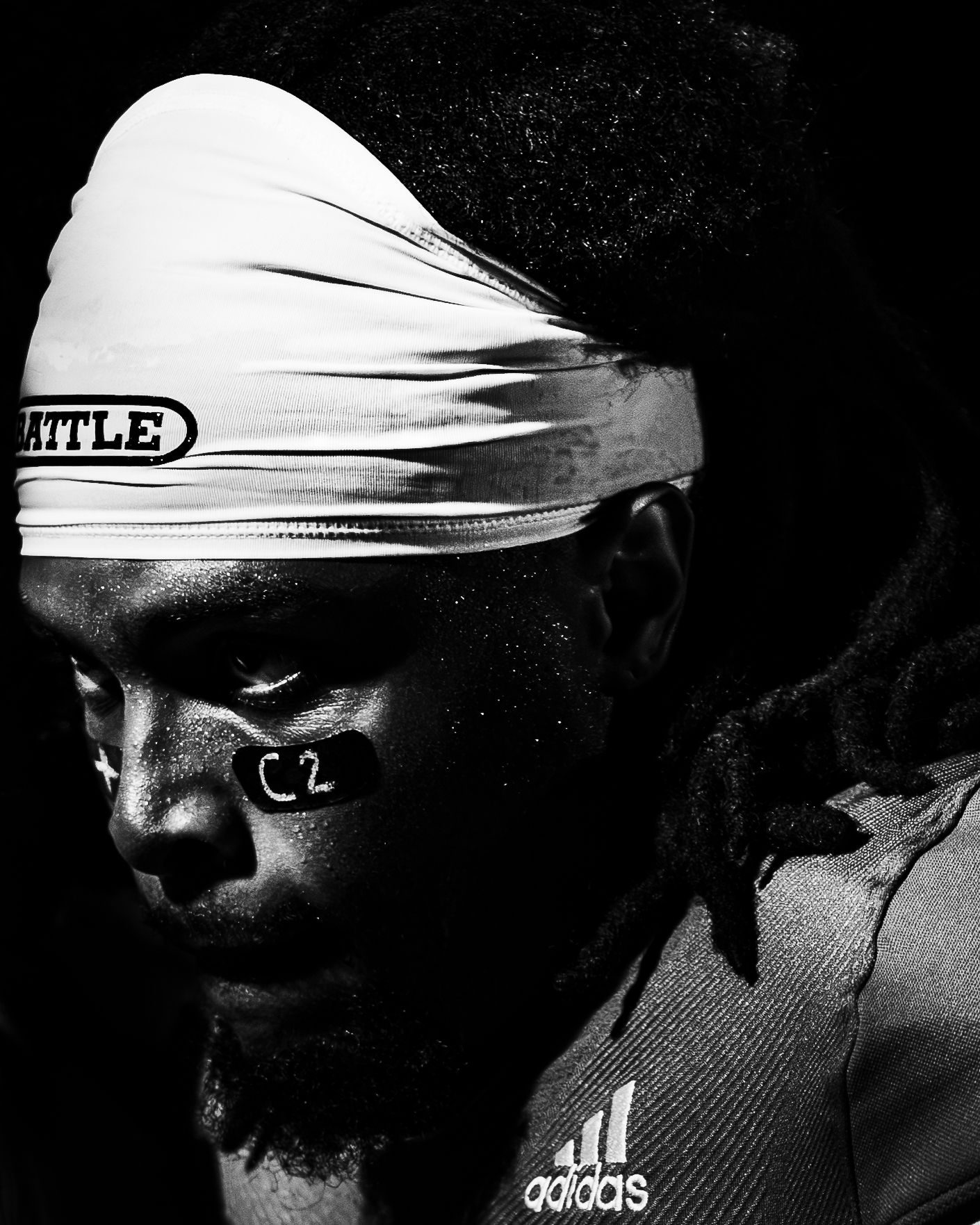 Black and white portrait of an athlete wearing an Adidas jersey and Battle headband with dreadlocks.