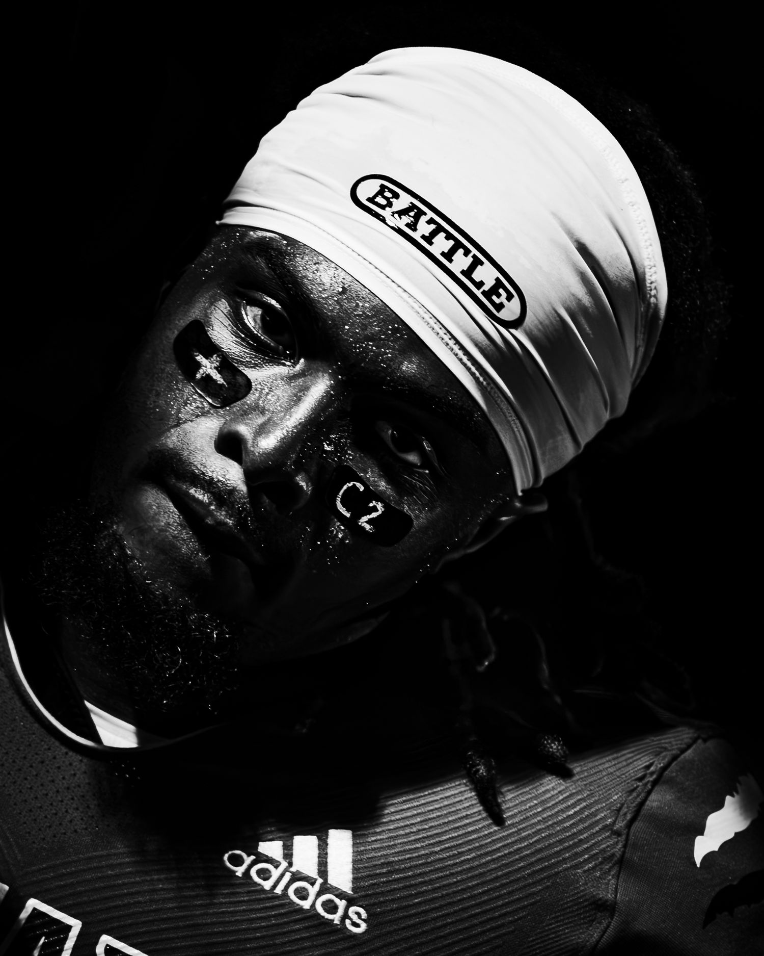 Black and white portrait of an athlete wearing a Battle branded headband and Adidas jersey, with sweat on face.