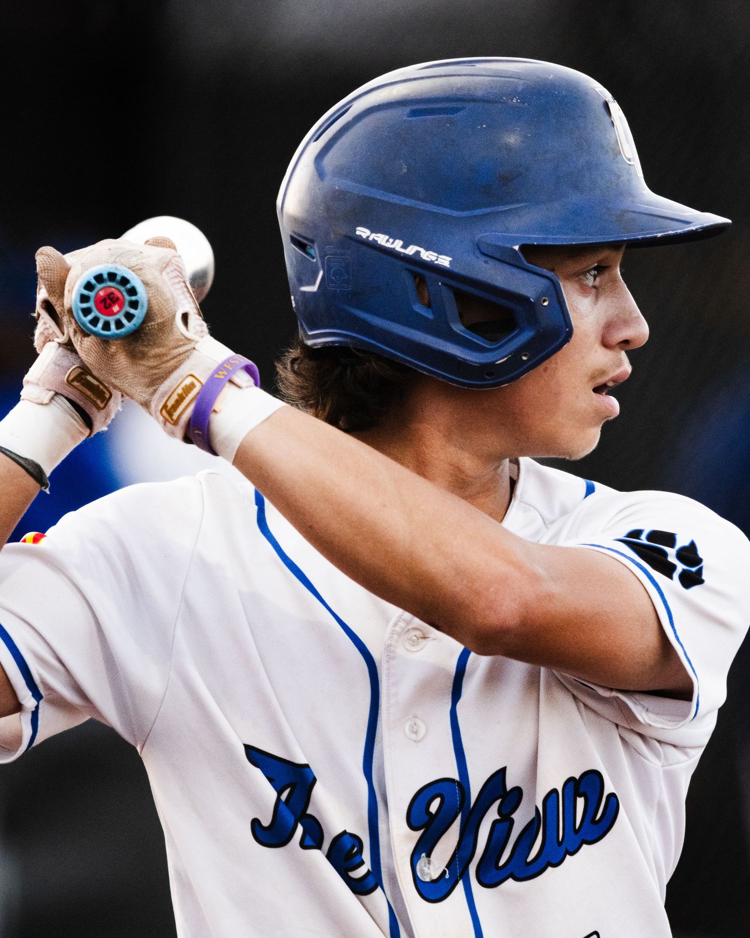 Baseball player in blue helmet and jersey holds bat ready to swing during a game.