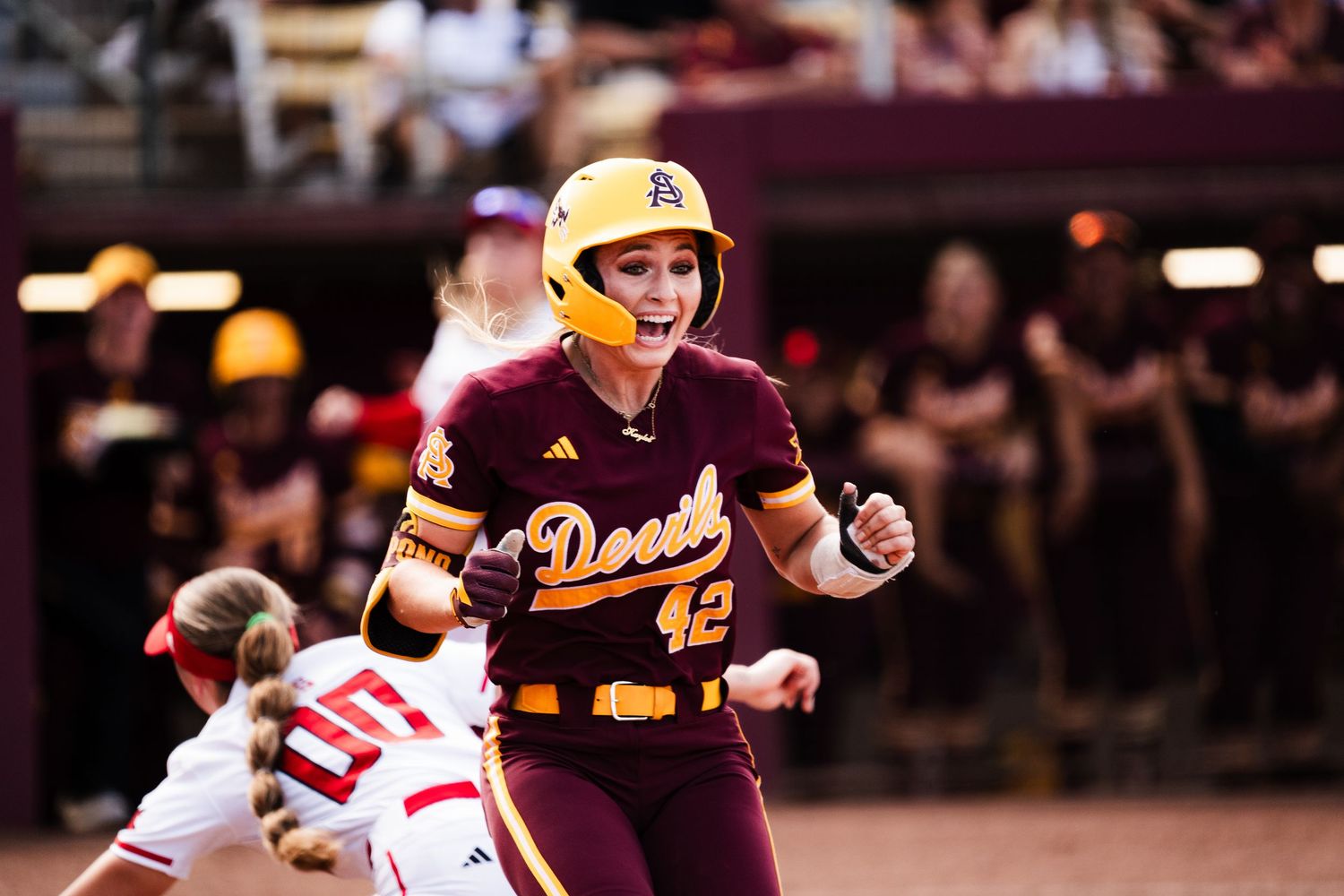 Arizona State Sun Devils softball player #42 celebrates in maroon and gold uniform during an exciting college softball game.