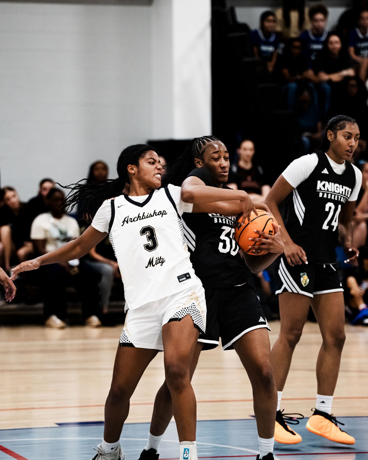 Archbishop Mitty player number 3 battles for the ball against Knights Basketball players during an intense girls basketball game.