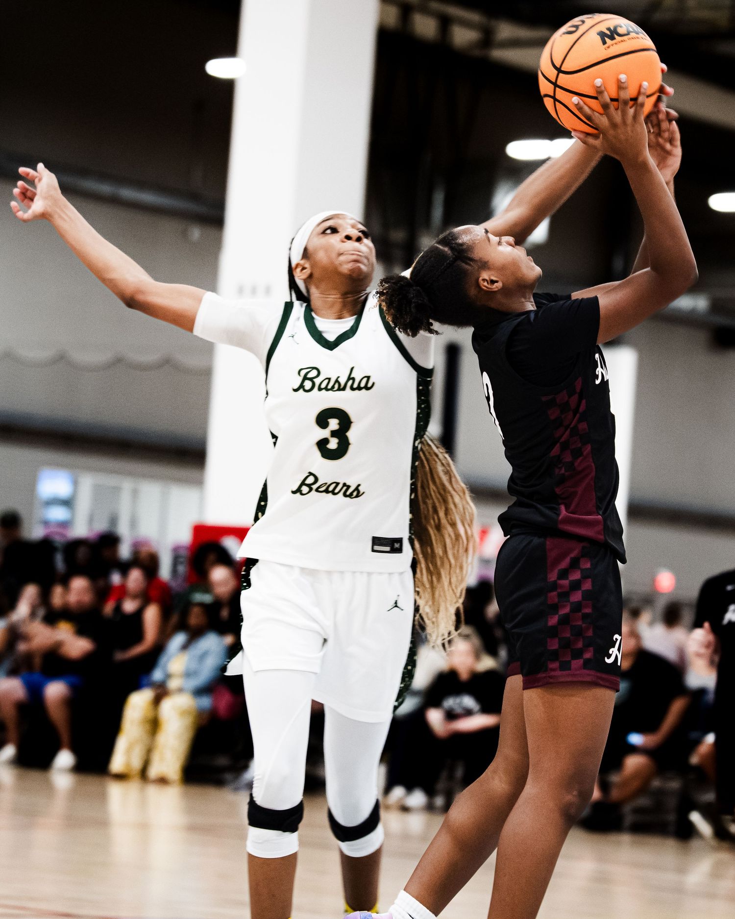 Basha Bears player number 3 contests a shot during an intense girls high school basketball game indoors.