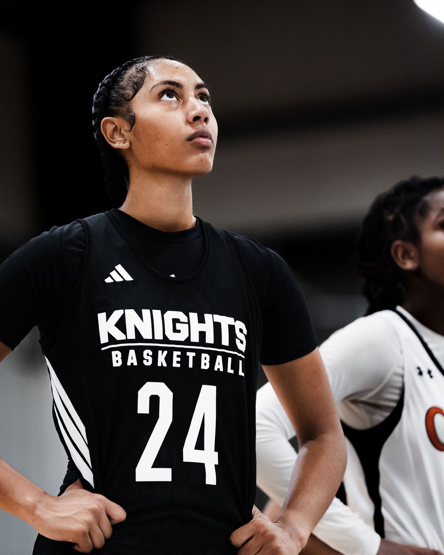 Female basketball player wearing Knights Basketball jersey number 24 stands on court during game.
