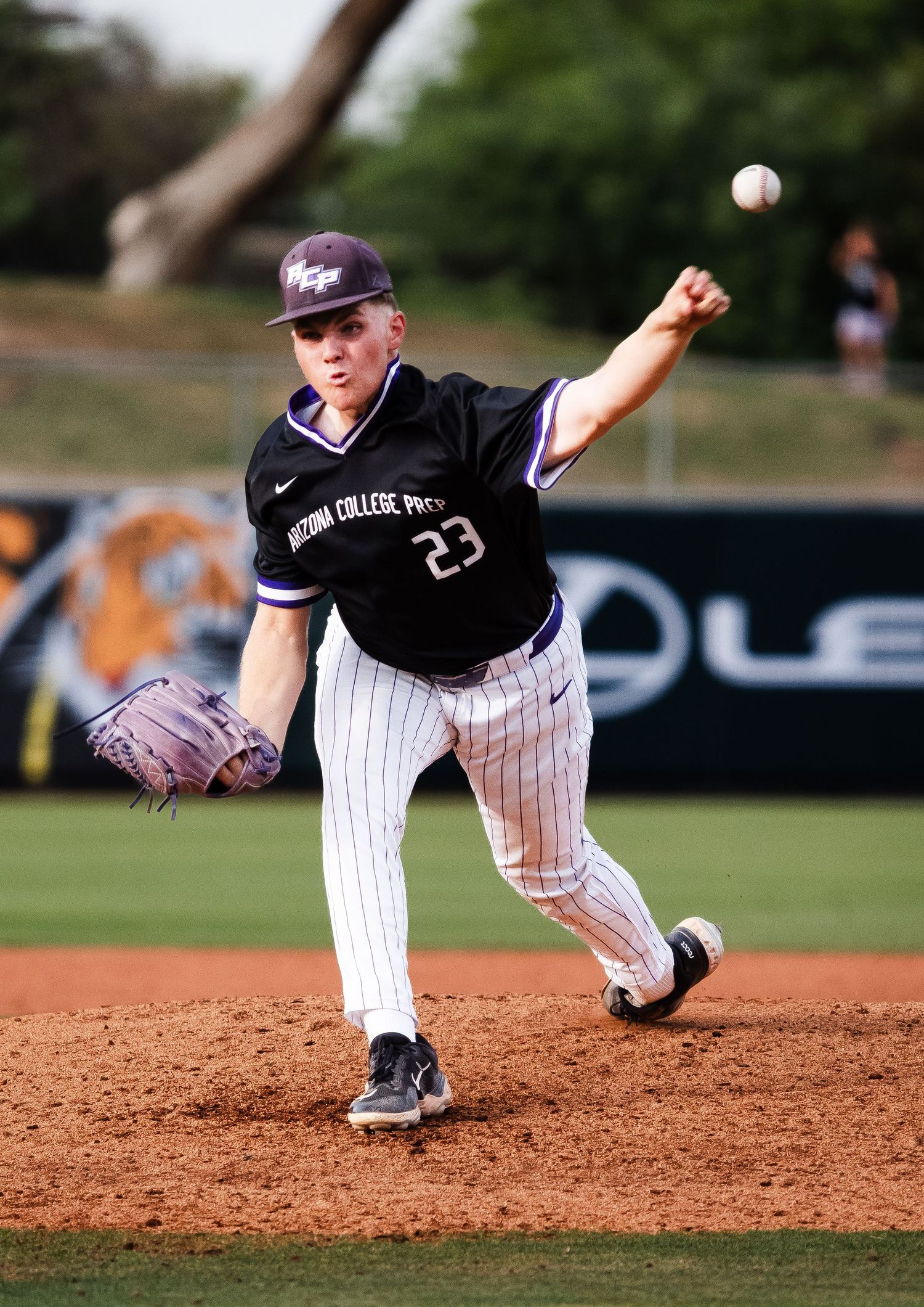 College baseball pitcher #23 in black uniform mid-throw on mound.