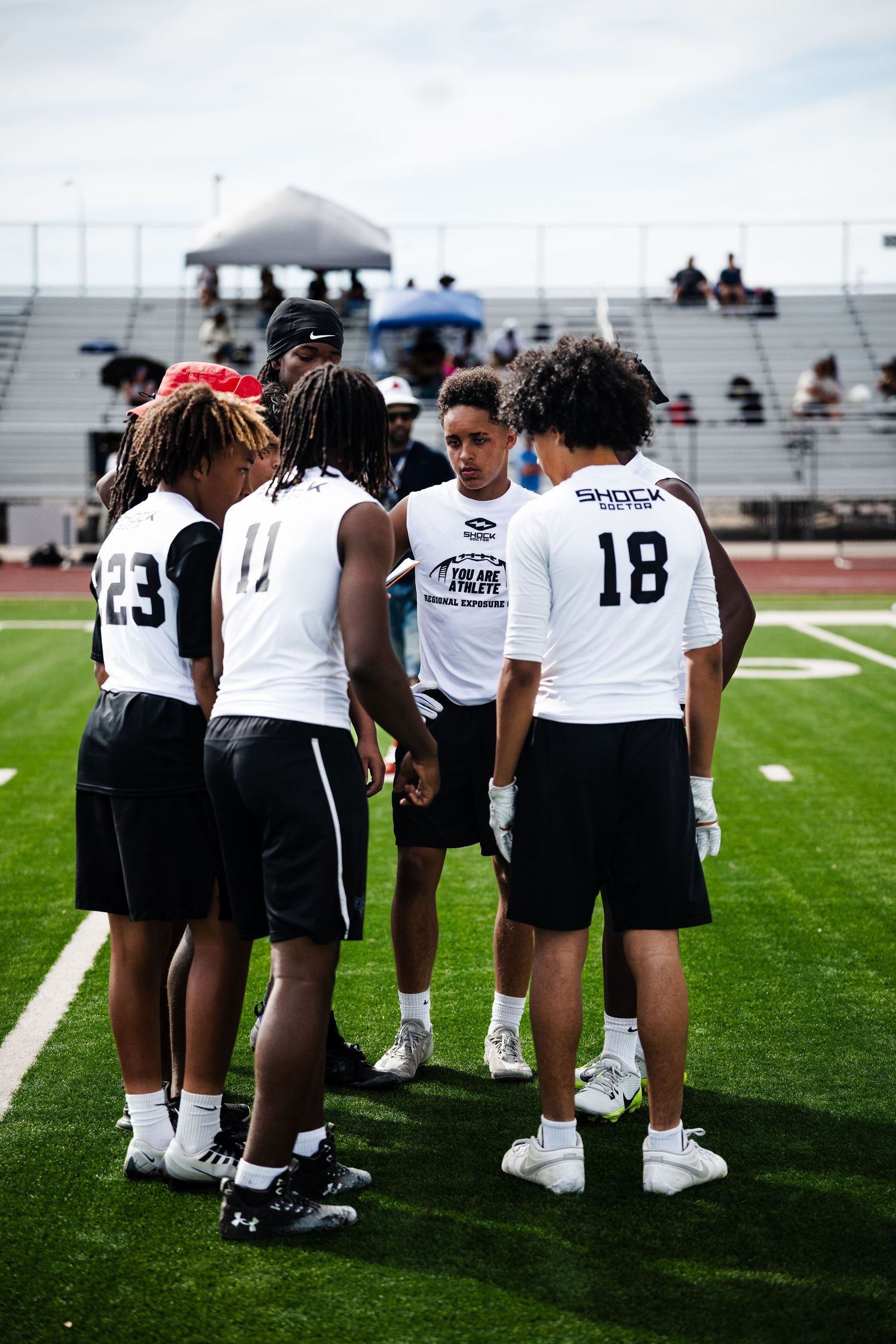 Football players in black and white uniforms huddle together on green turf during game day.