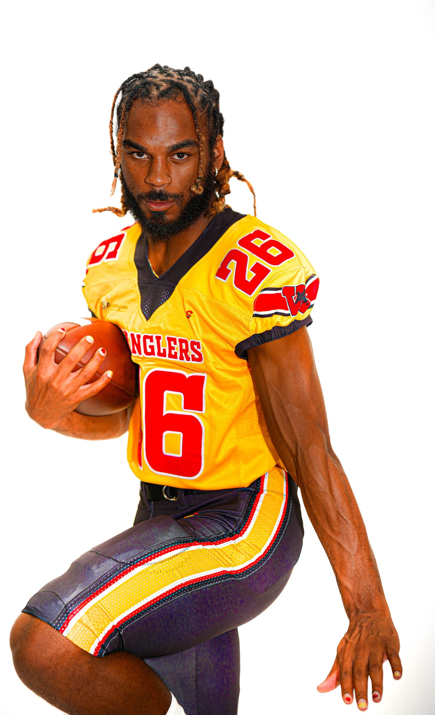 Football player #26 in gold Wranglers jersey holds ball in studio pose.