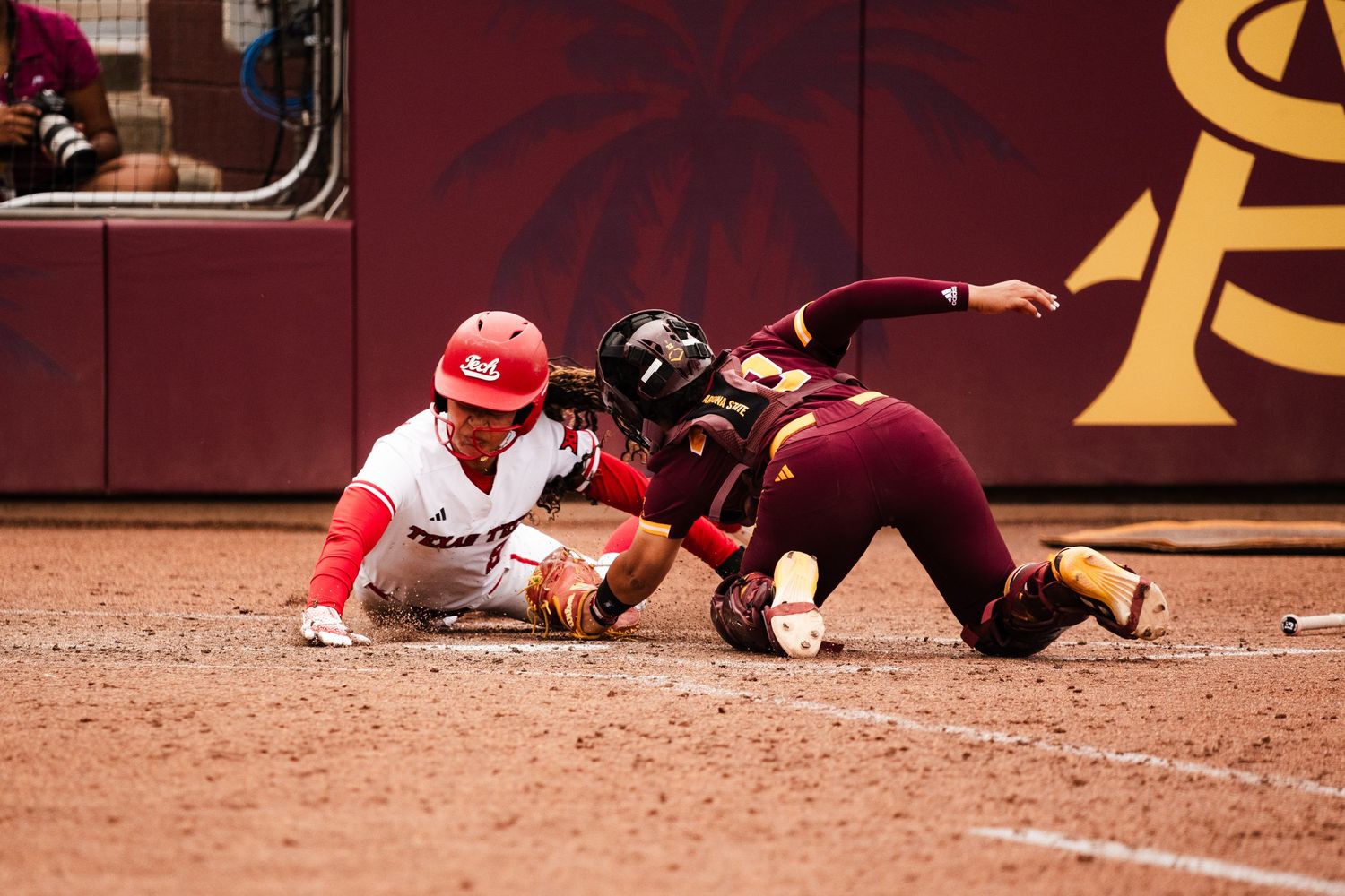 A softball player slides into base as an ASU defender applies the tag during a college game.