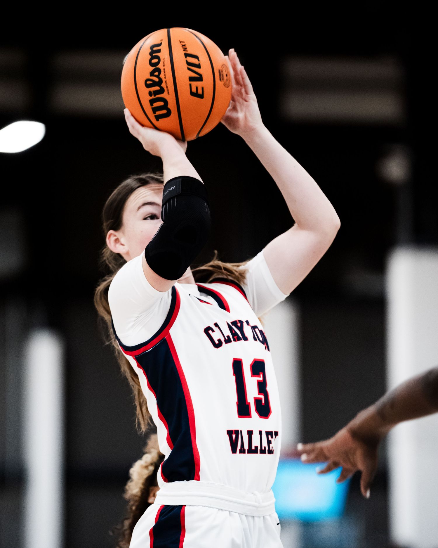 Female basketball player #13 in Clayton Valley uniform shoots a Wilson EVO basketball during a game.