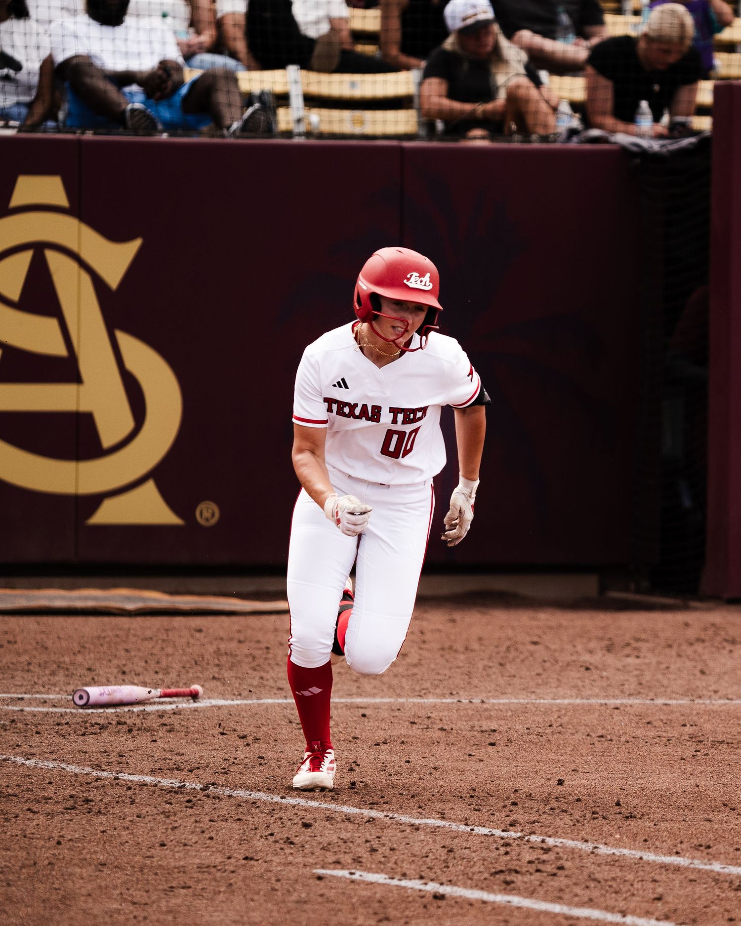 Texas Tech softball player in white uniform sprinting the bases during a college game at Arizona State.