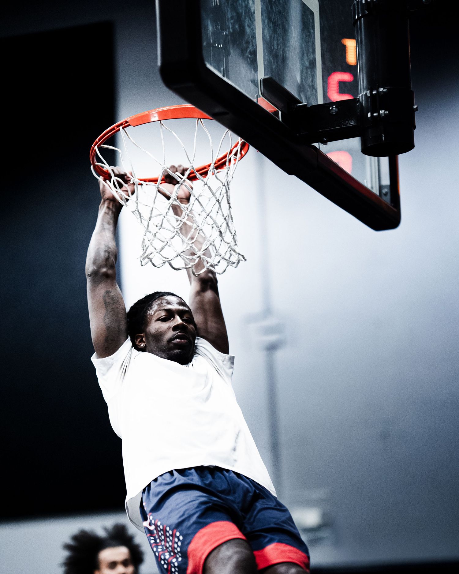 An athlete powerfully dunks a basketball through the hoop during an indoor basketball game.