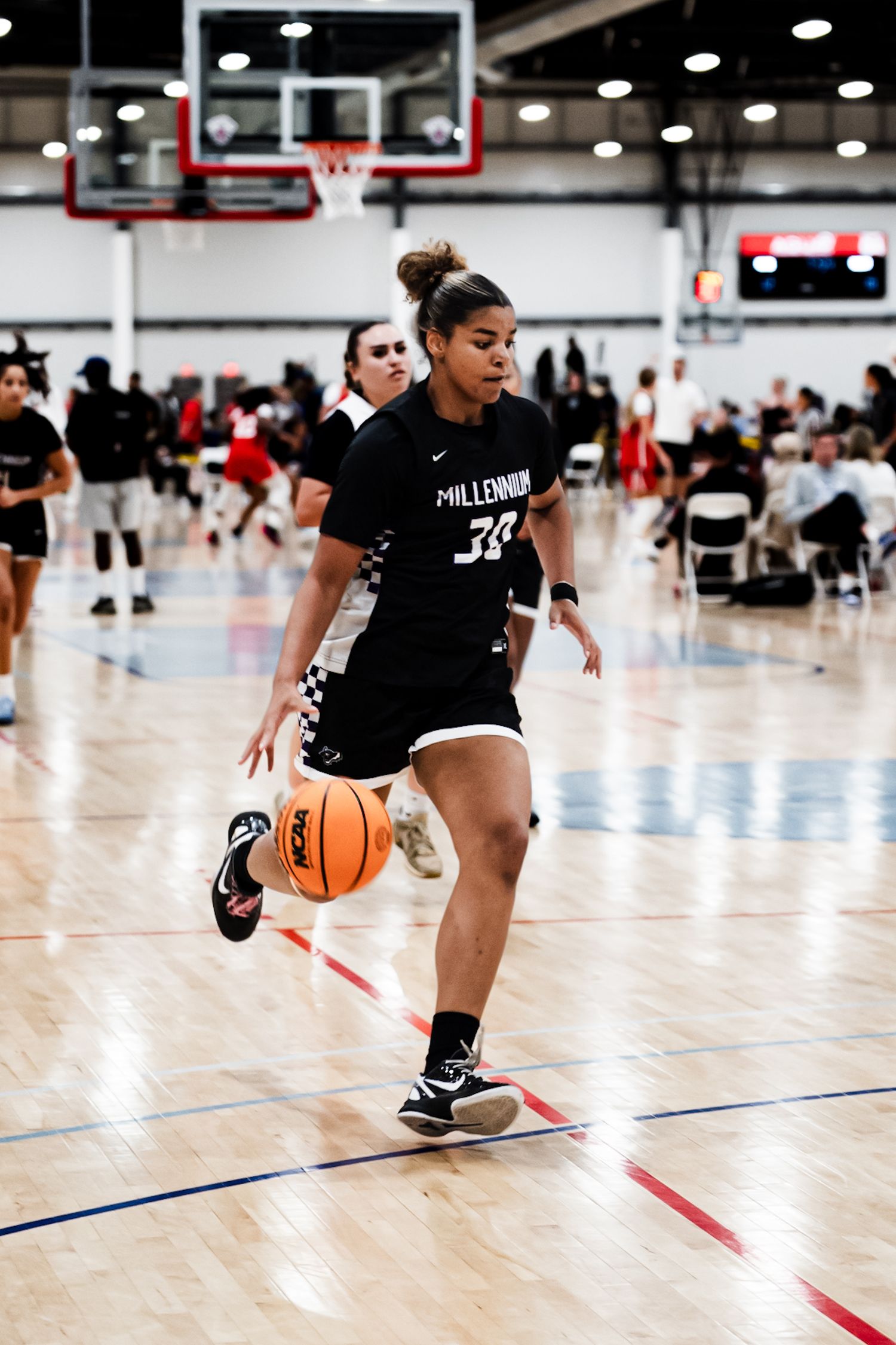 A Millennium girls basketball player wearing number 33 dribbles the ball upcourt during a high school basketball tournament game.