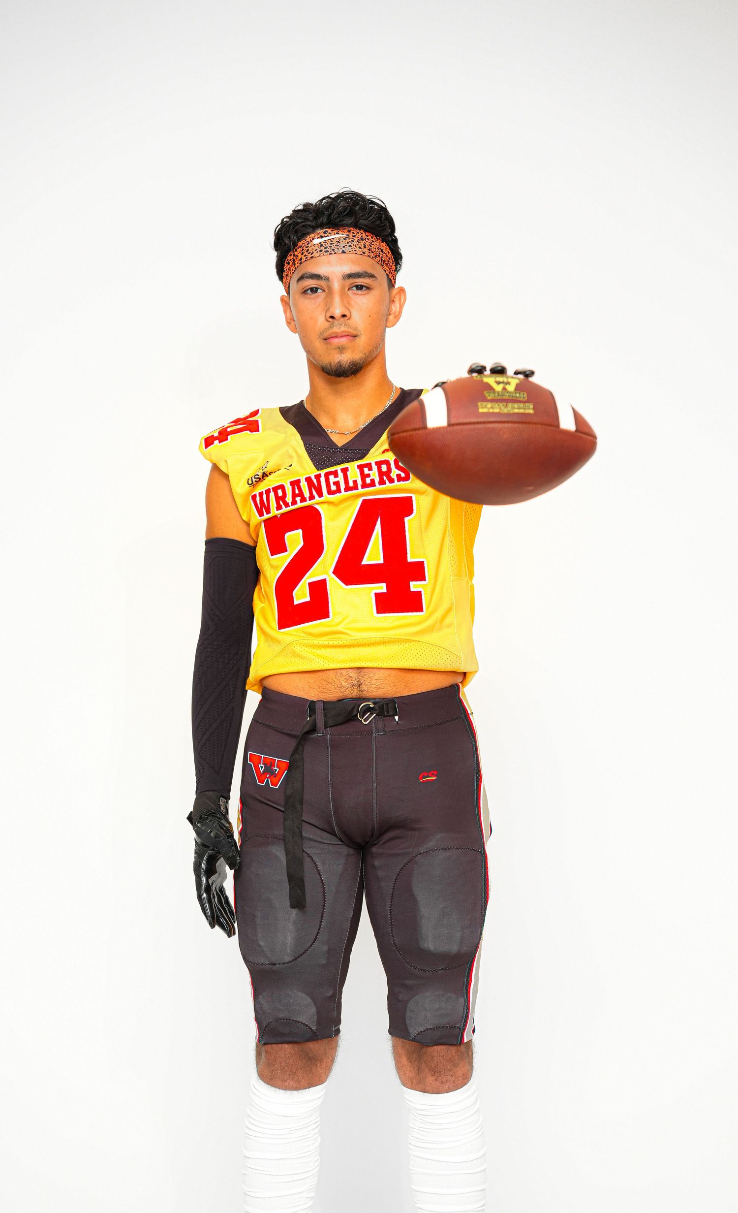 Football player in yellow Wranglers #24 jersey holds a football, wearing black gloves and arm sleeve.