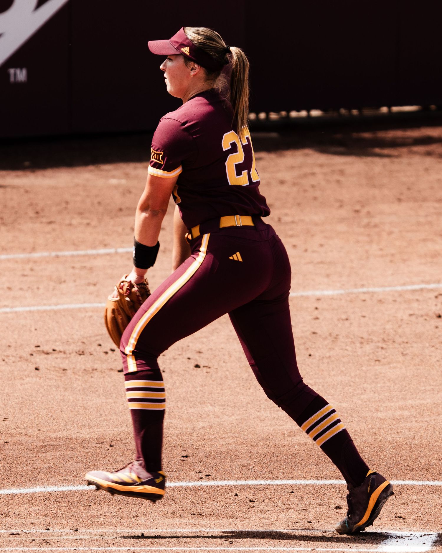 ASU softball player #22 in maroon Adidas uniform strides across infield dirt.