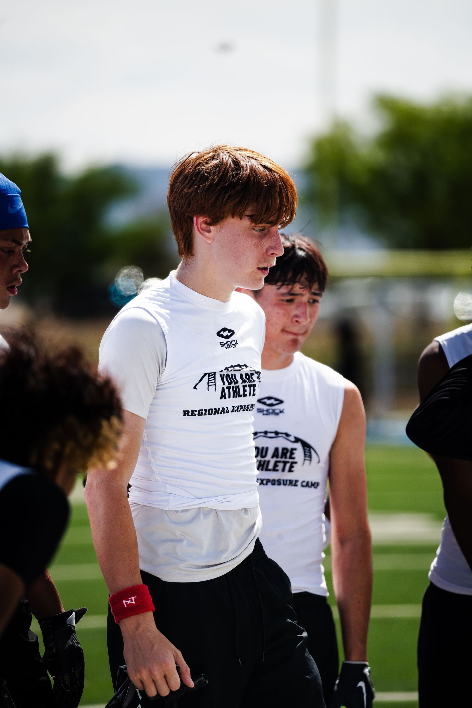 Two young athletes wearing You Are Athlete Regional Camp shirts stand together on a football field.