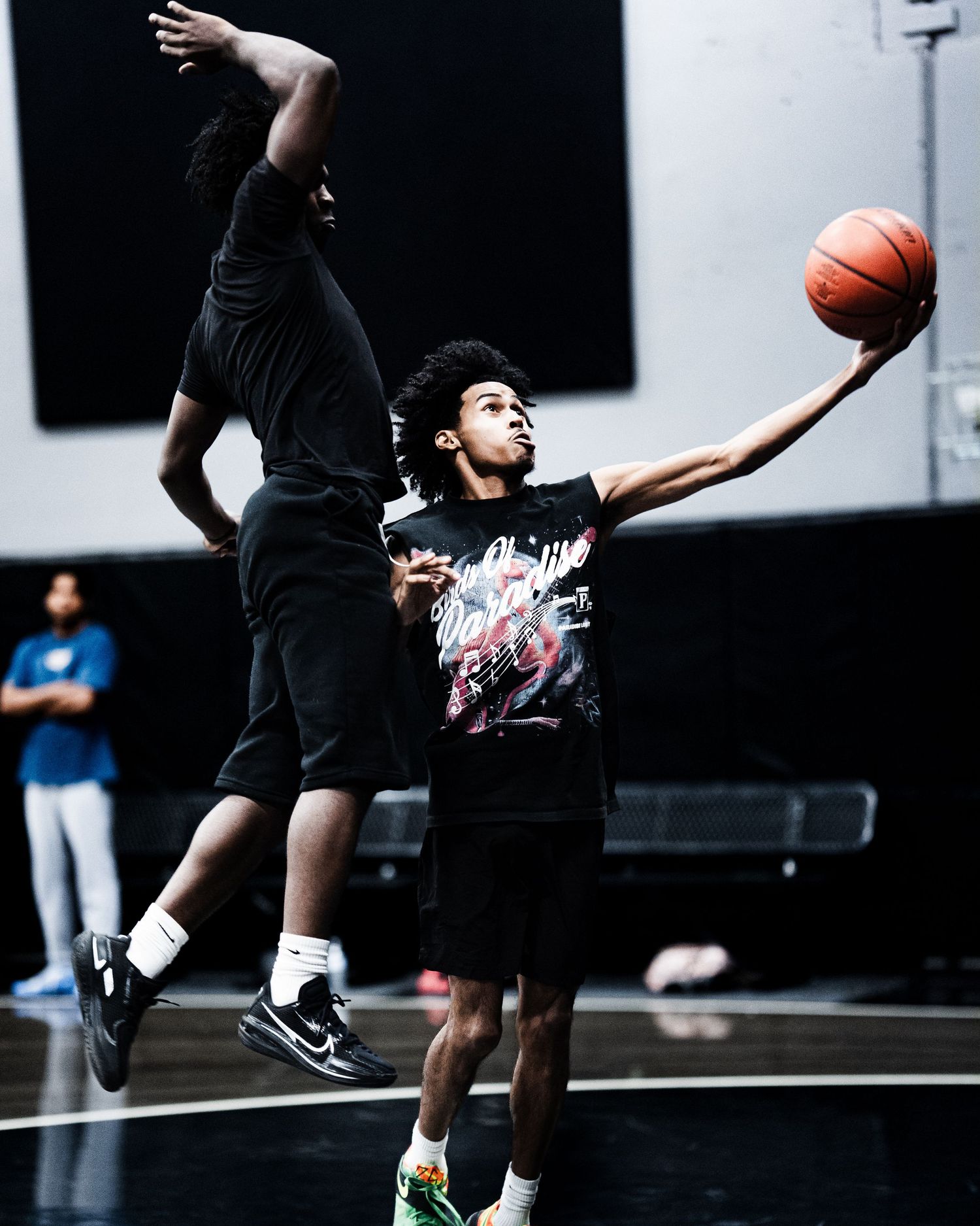 A young basketball player extends for a layup while being defended during an indoor practice game.