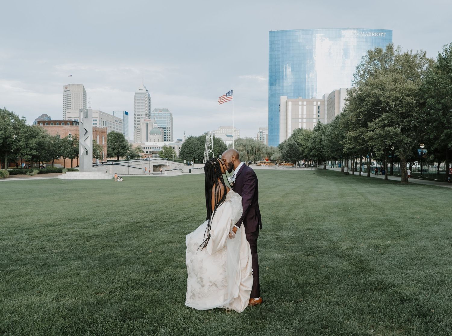 Bride and groom posing by the water with a soft Indiana skyline backdrop, captured in a timeless, modern portrait by Noelle Moss Photography