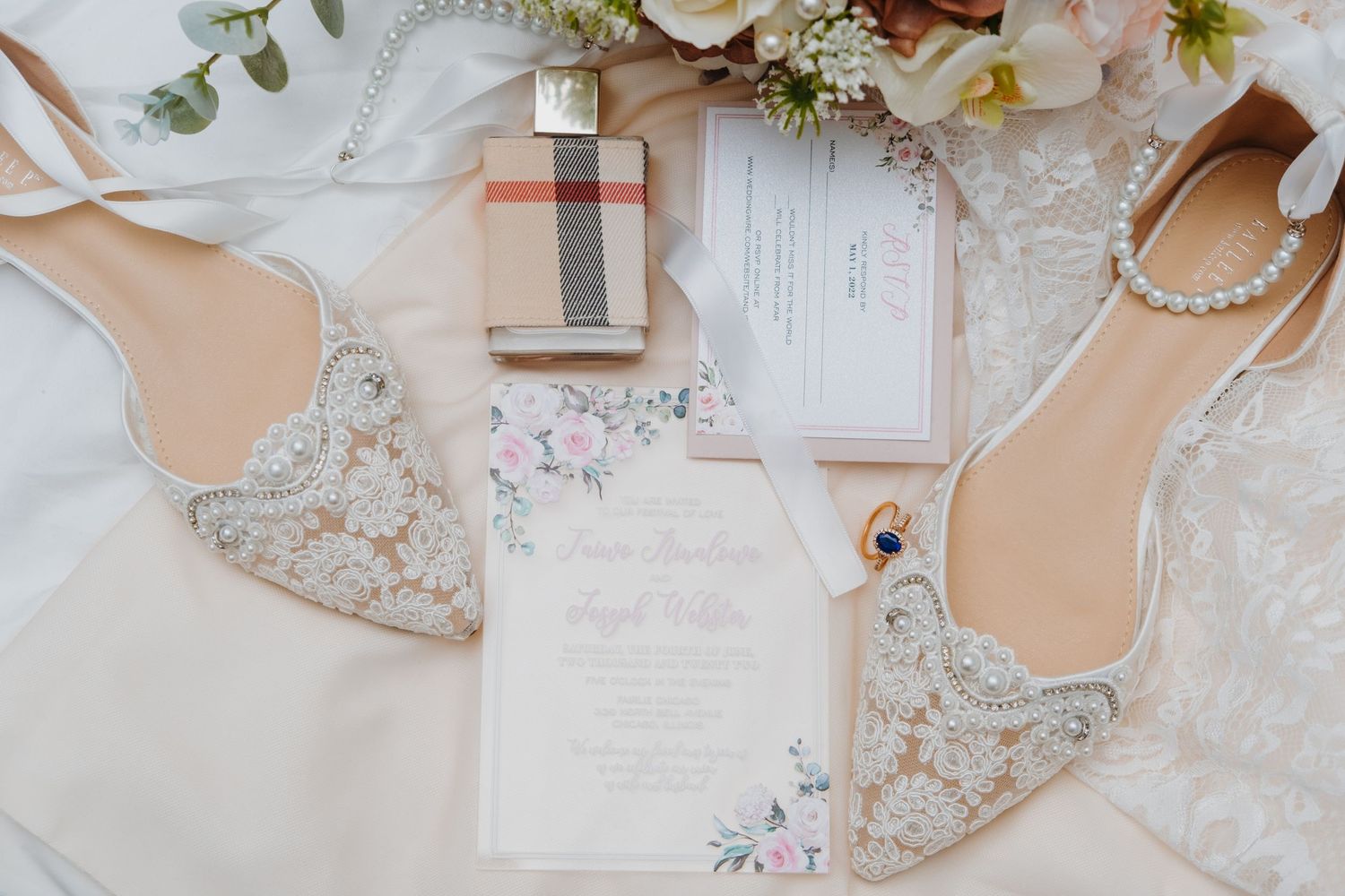 Wedding invitation flat lay with perfume, shoes, and floral details captured by Noelle Moss Photography