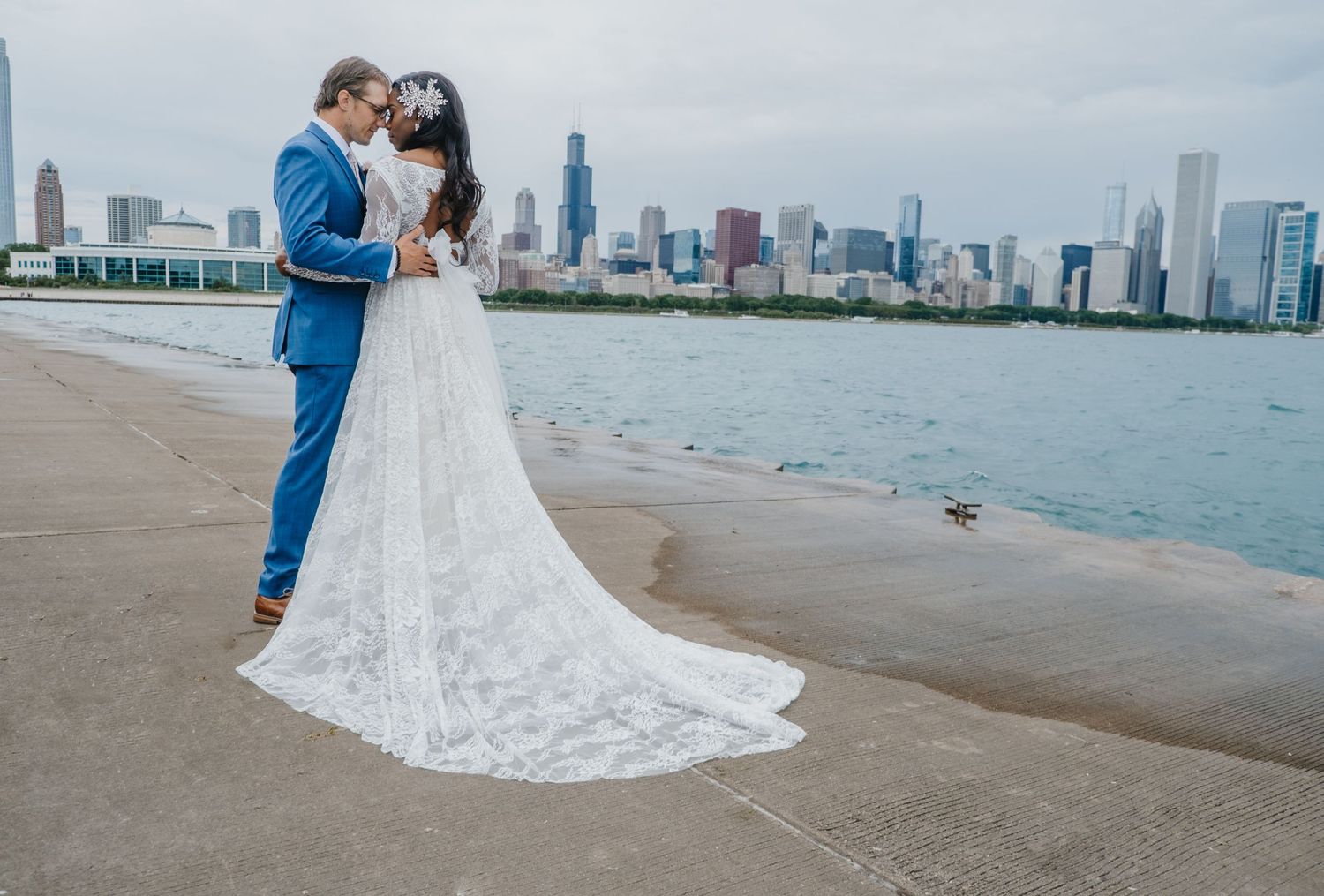 Bride and groom posing by the water with a soft Chicago skyline backdrop, captured in a timeless, modern portrait by Noelle Moss Photography
