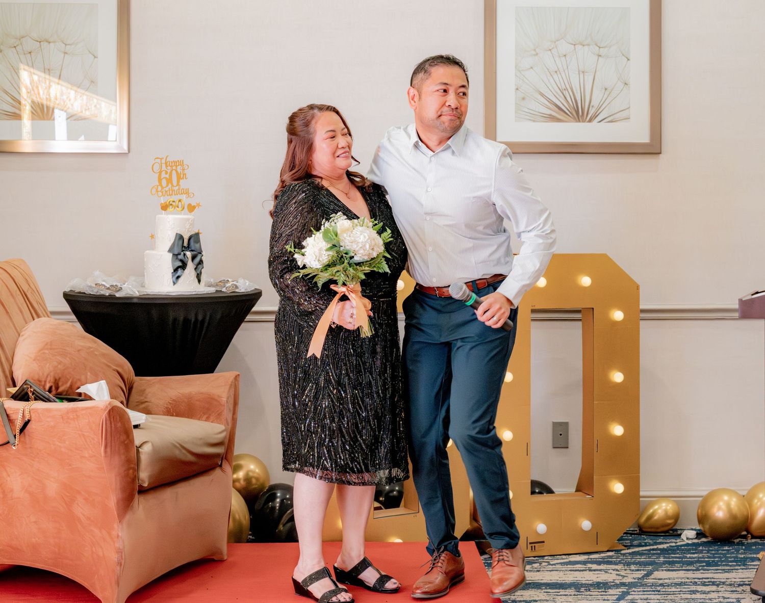 Couple posing together near illuminated number 1 marquee sign at birthday celebration.