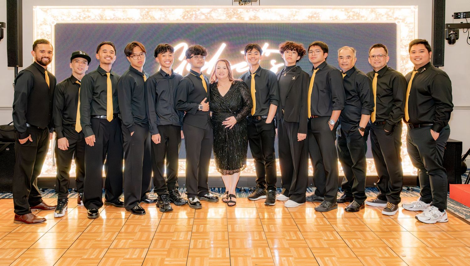 Large group of men in black and gold attire posing at a formal celebration.
