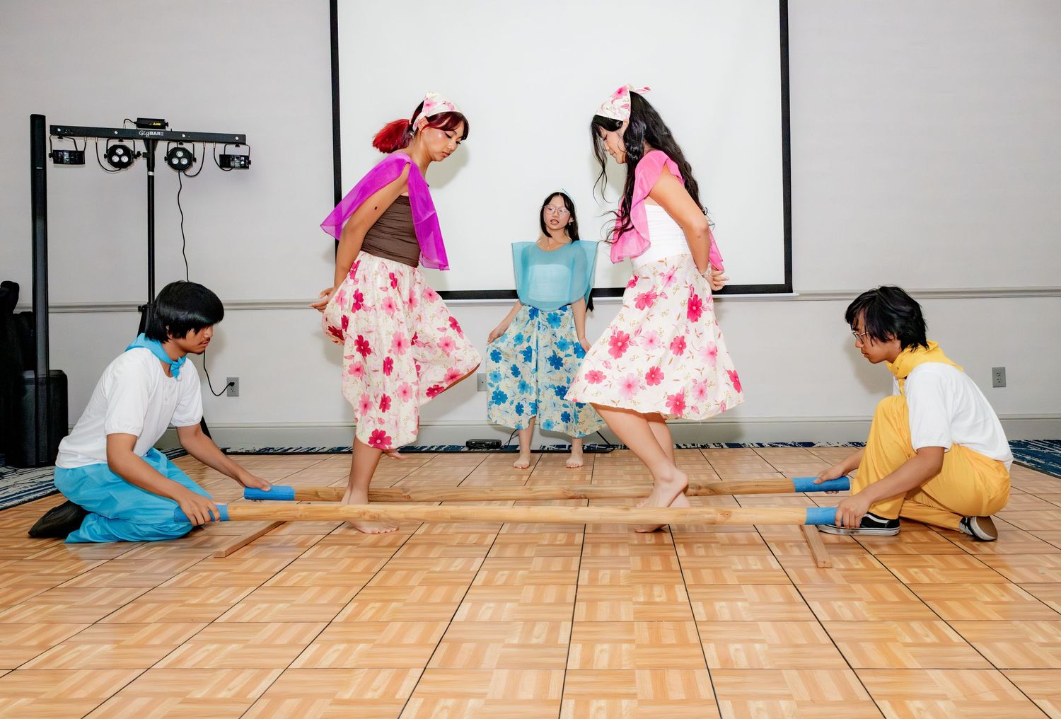 Traditional Filipino folk dancers performing the Tinikling bamboo dance at a cultural event.