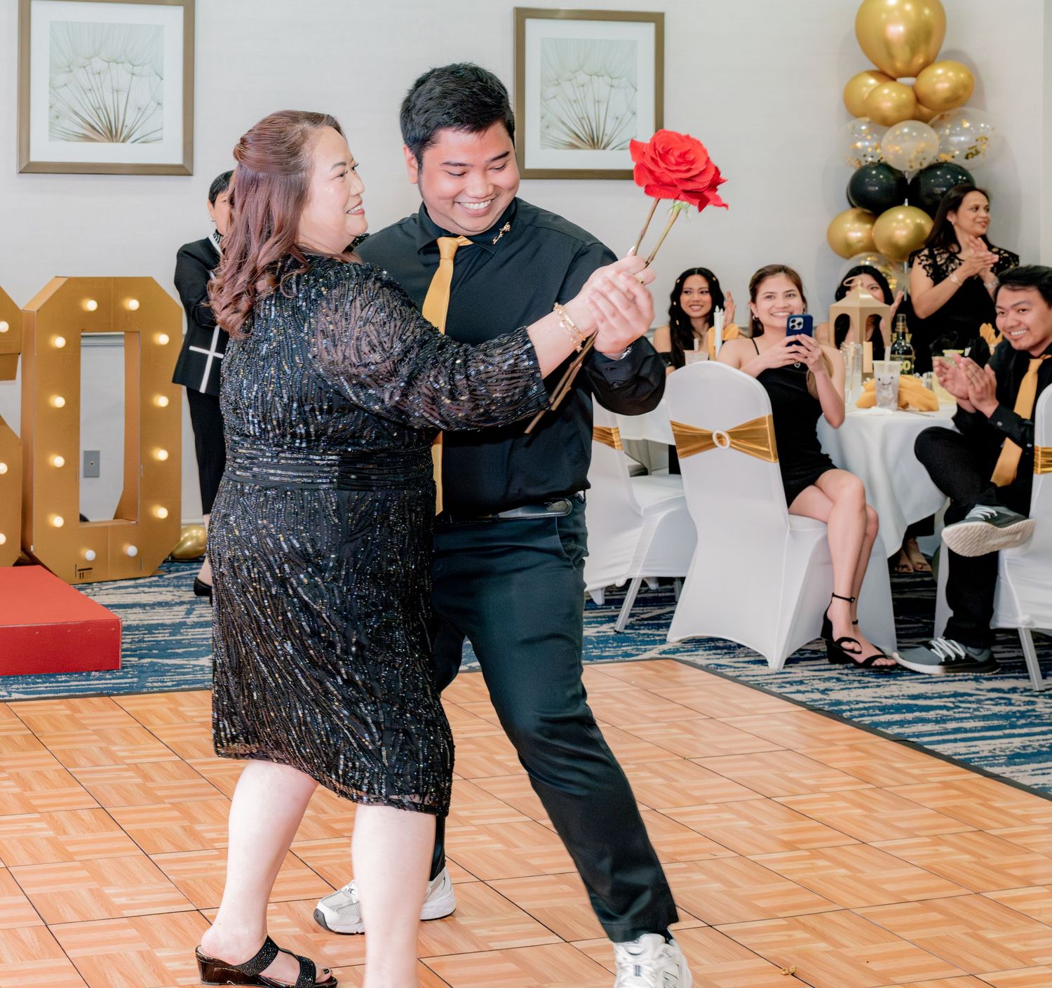 Couple dancing with red rose at elegant 60th birthday party celebration.