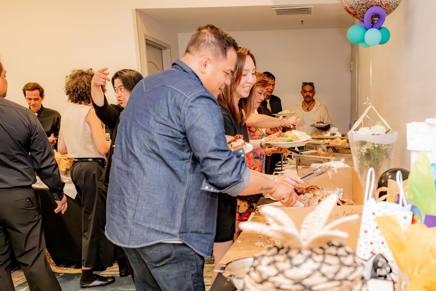 Guests serving themselves at a buffet during an indoor celebration event.
