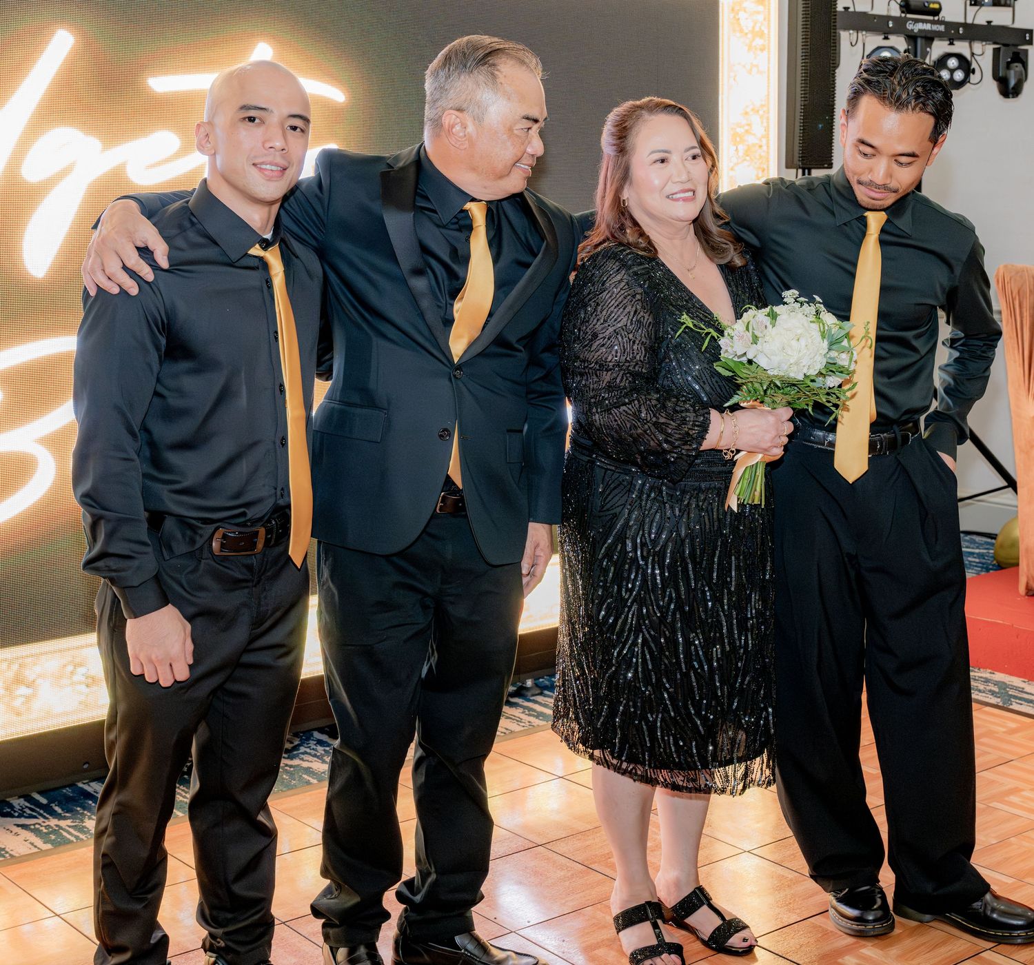 Group of four people posing together at a formal birthday celebration event.