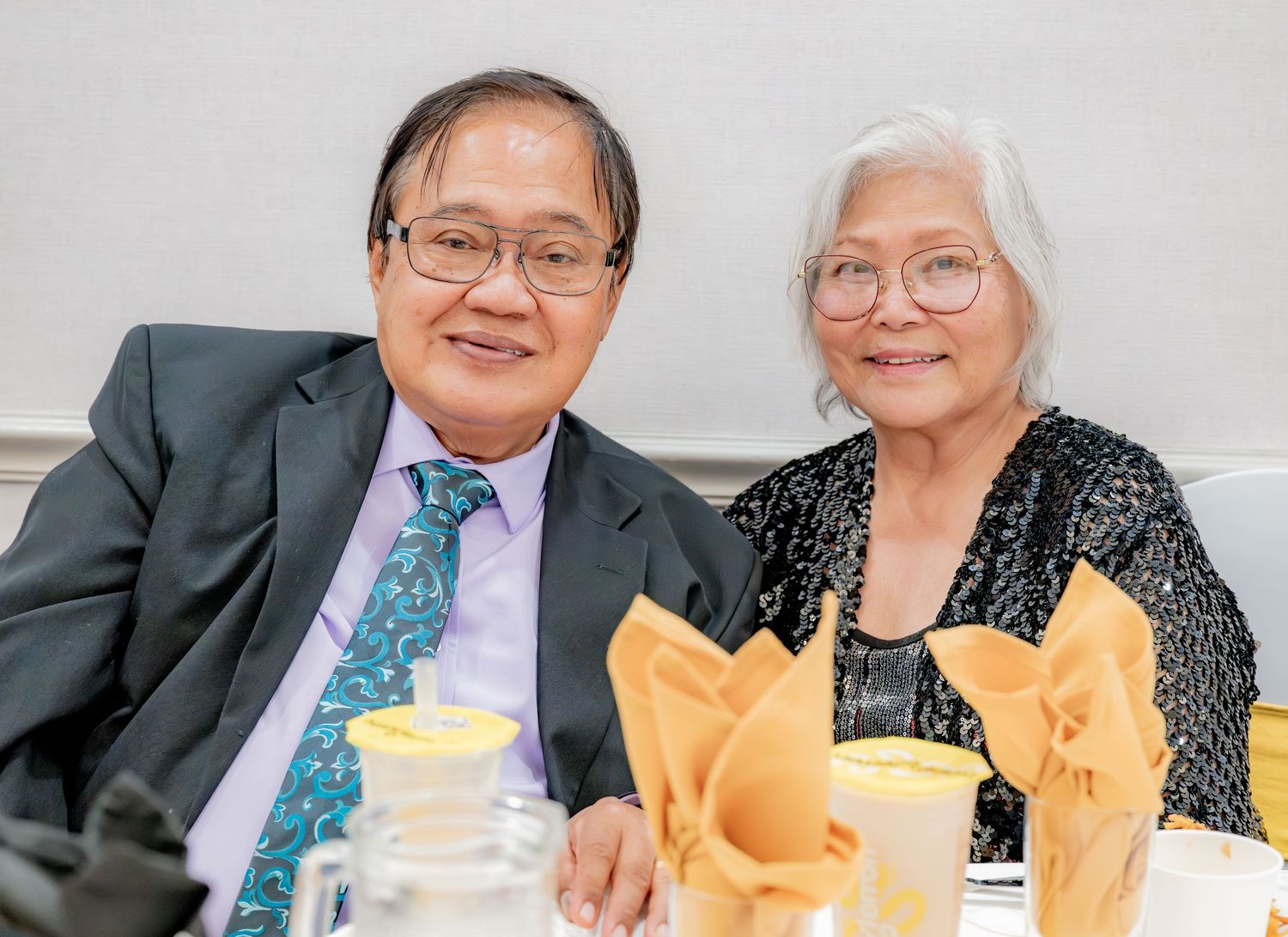 Elderly couple smiling together at a formal dinner event.