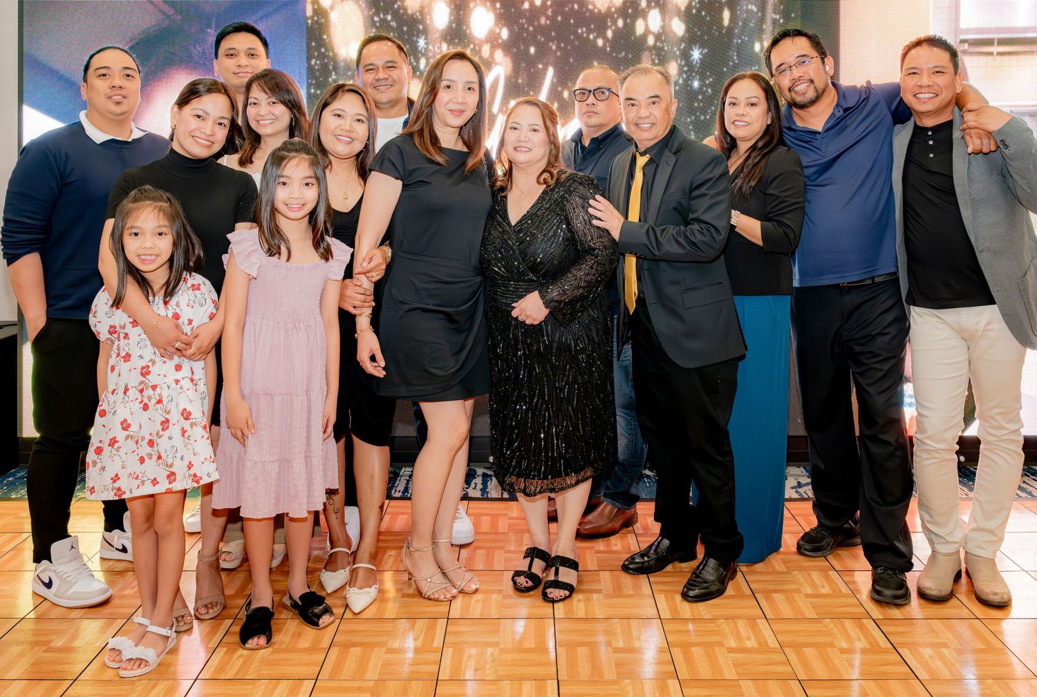 Large family group celebrating together at a formal black and gold themed party.