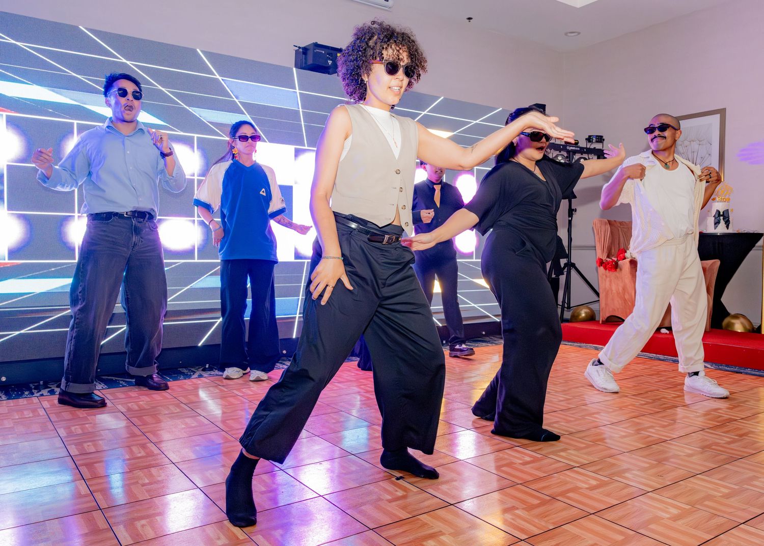 Dancers performing energetically on a dance floor at a vibrant indoor party event.