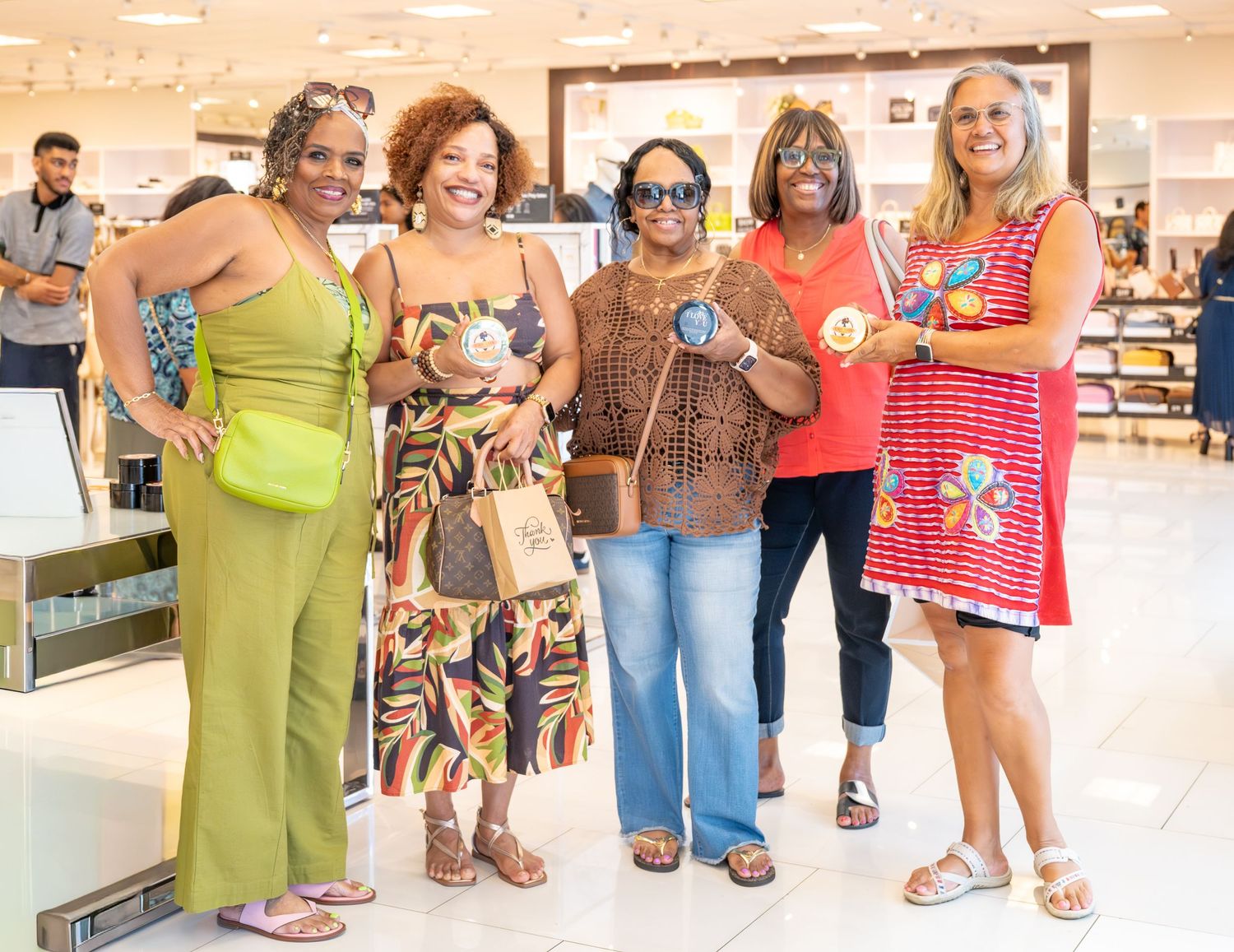 Five women pose together smiling inside a retail store.