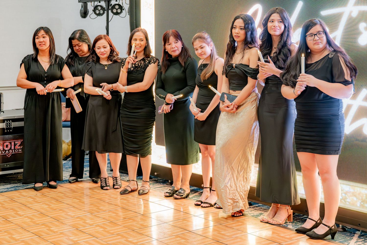 Group of women in black dresses posing together at an elegant birthday celebration event.