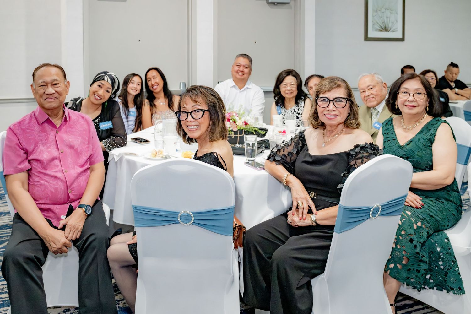 Guests seated at round tables during an elegant indoor event in a bright, decorated banquet hall.