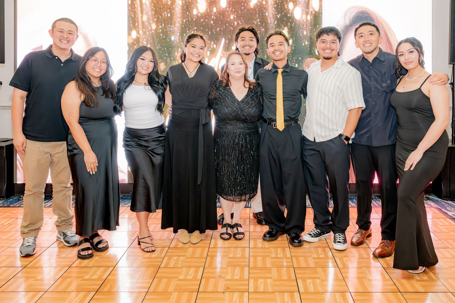 Group of friends posing together at a formal celebration event indoors.