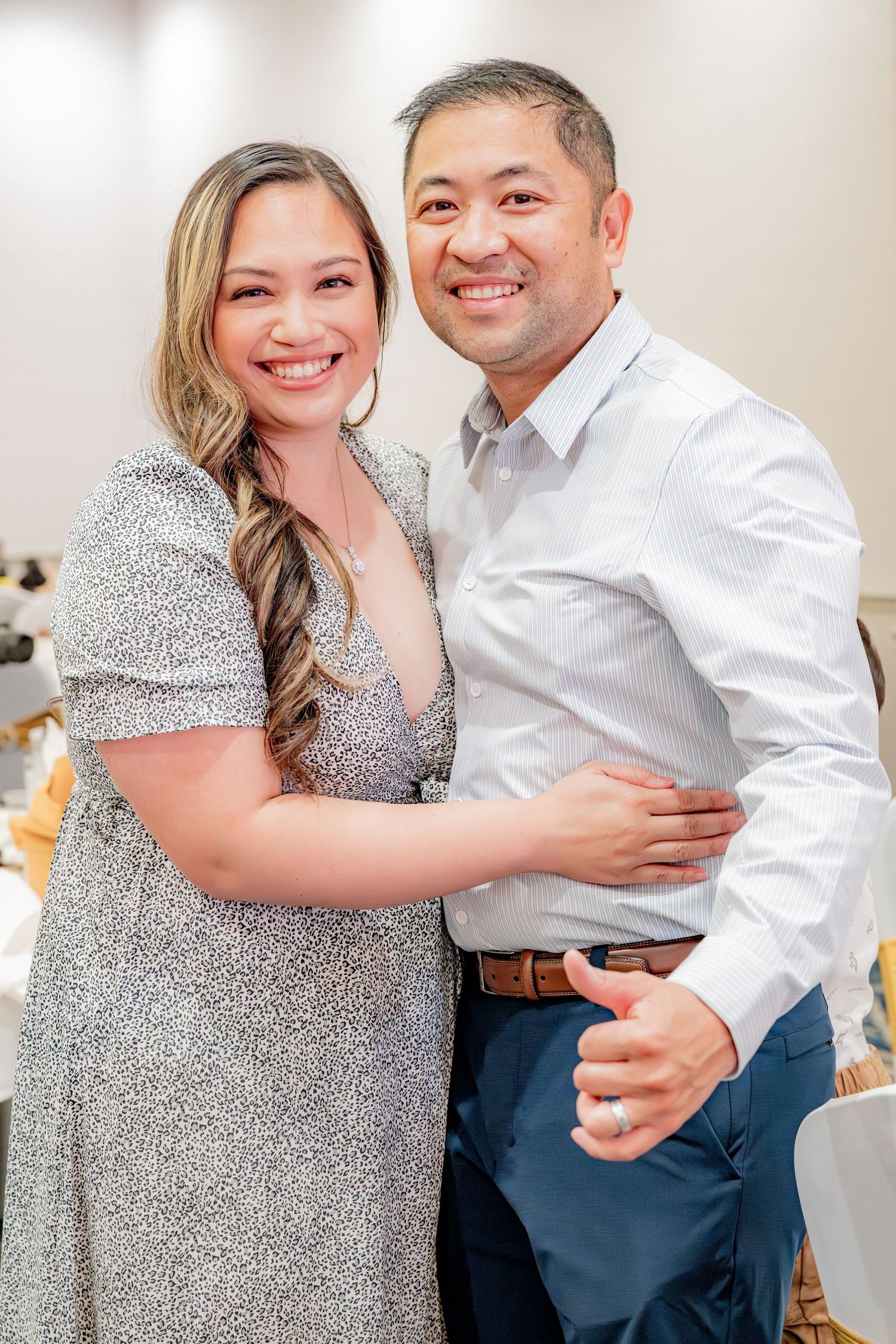Smiling couple embracing at an elegant indoor celebration.